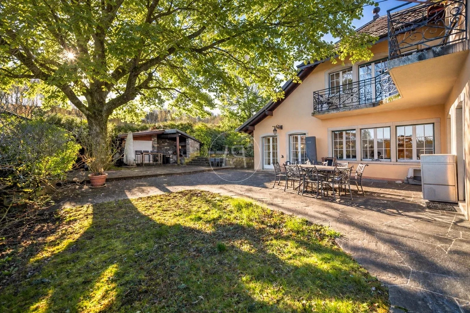 Sonnige Terrasse mit Garten und Hausfassade