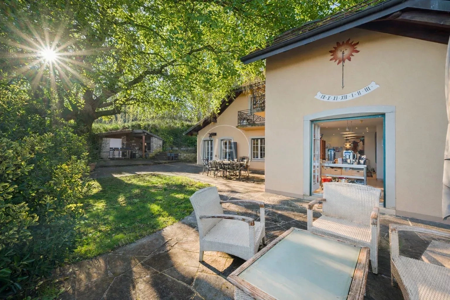 Sonnige Terrasse mit Garten und Hausfassade