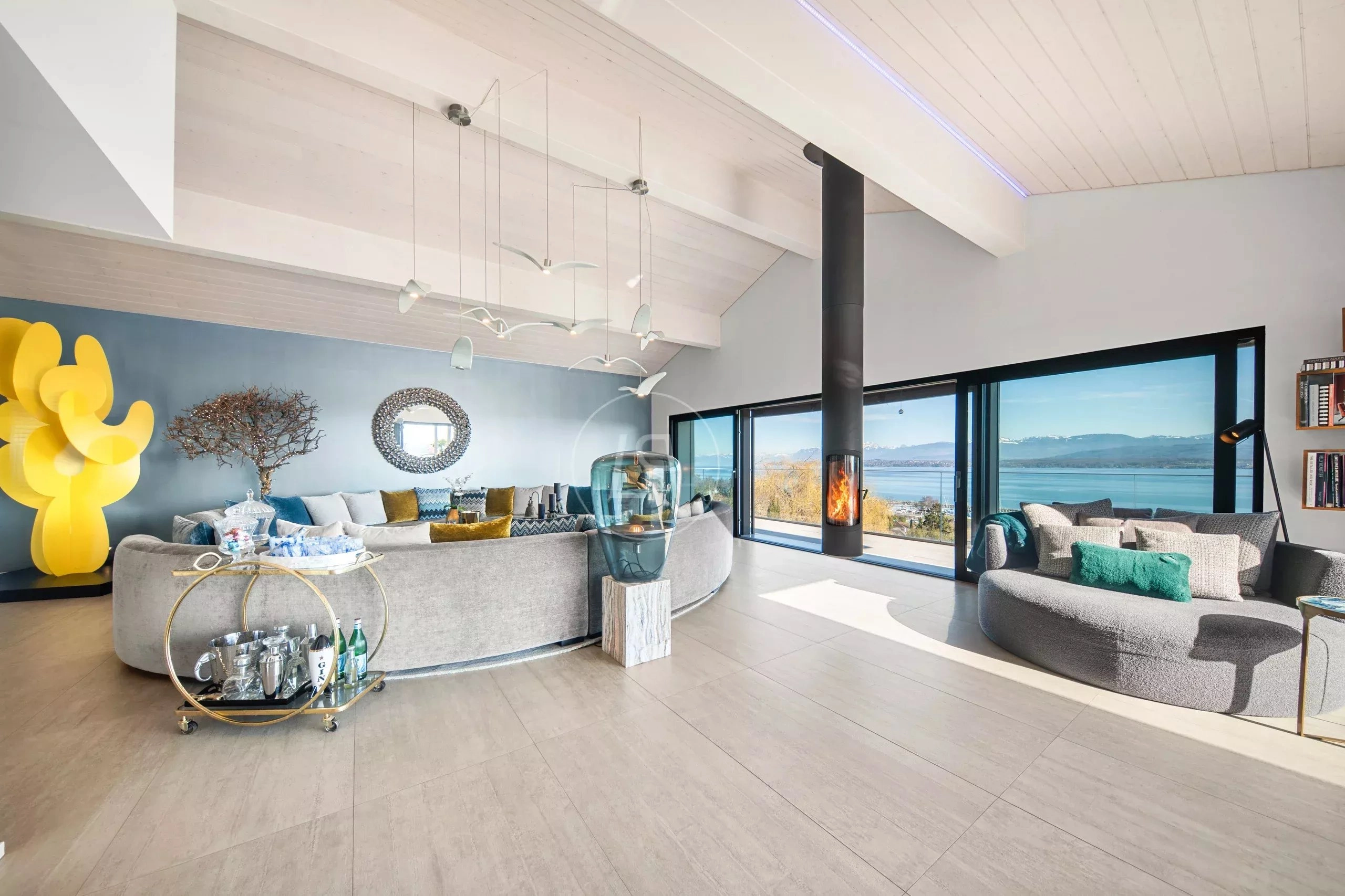 Großzügiges Panorama-Wohnzimmer mit Kamin und Seeblick