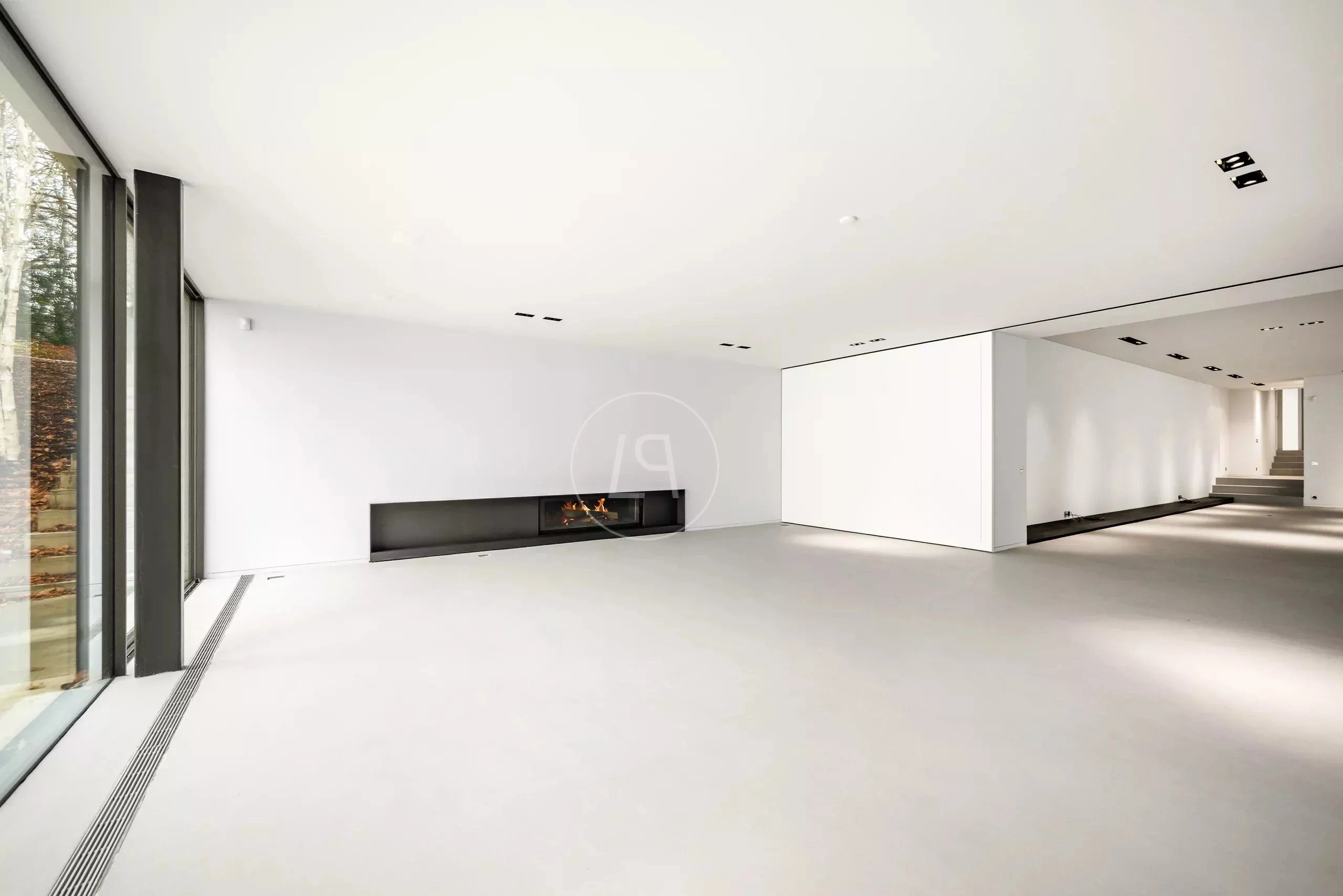 Großer minimalistischer Wohnraum mit Kamin und bodentiefen Fenstern