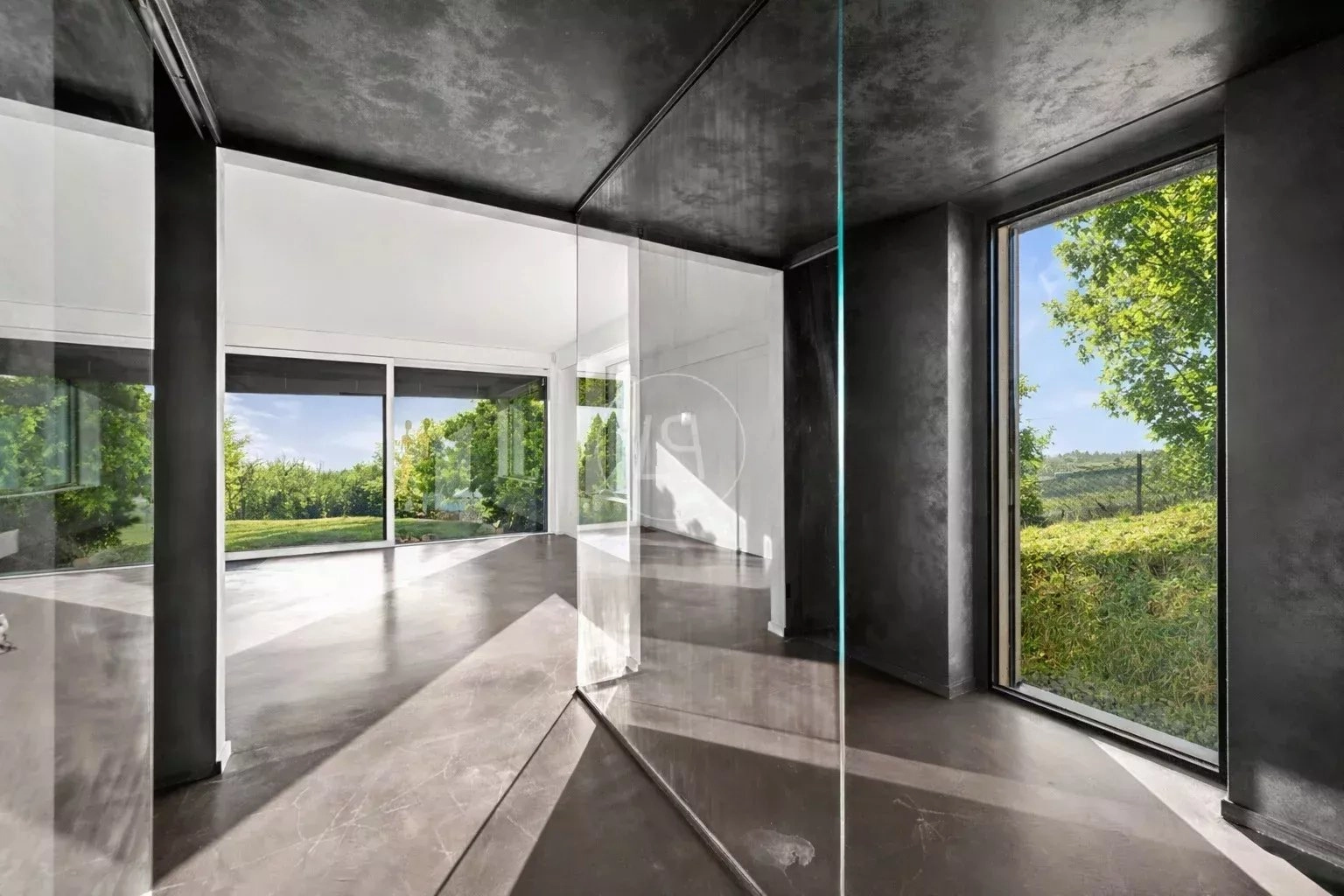 Modernes, lichtdurchflutetes Interieur mit dunklen Oberflächen und großflächiger Verglasung
