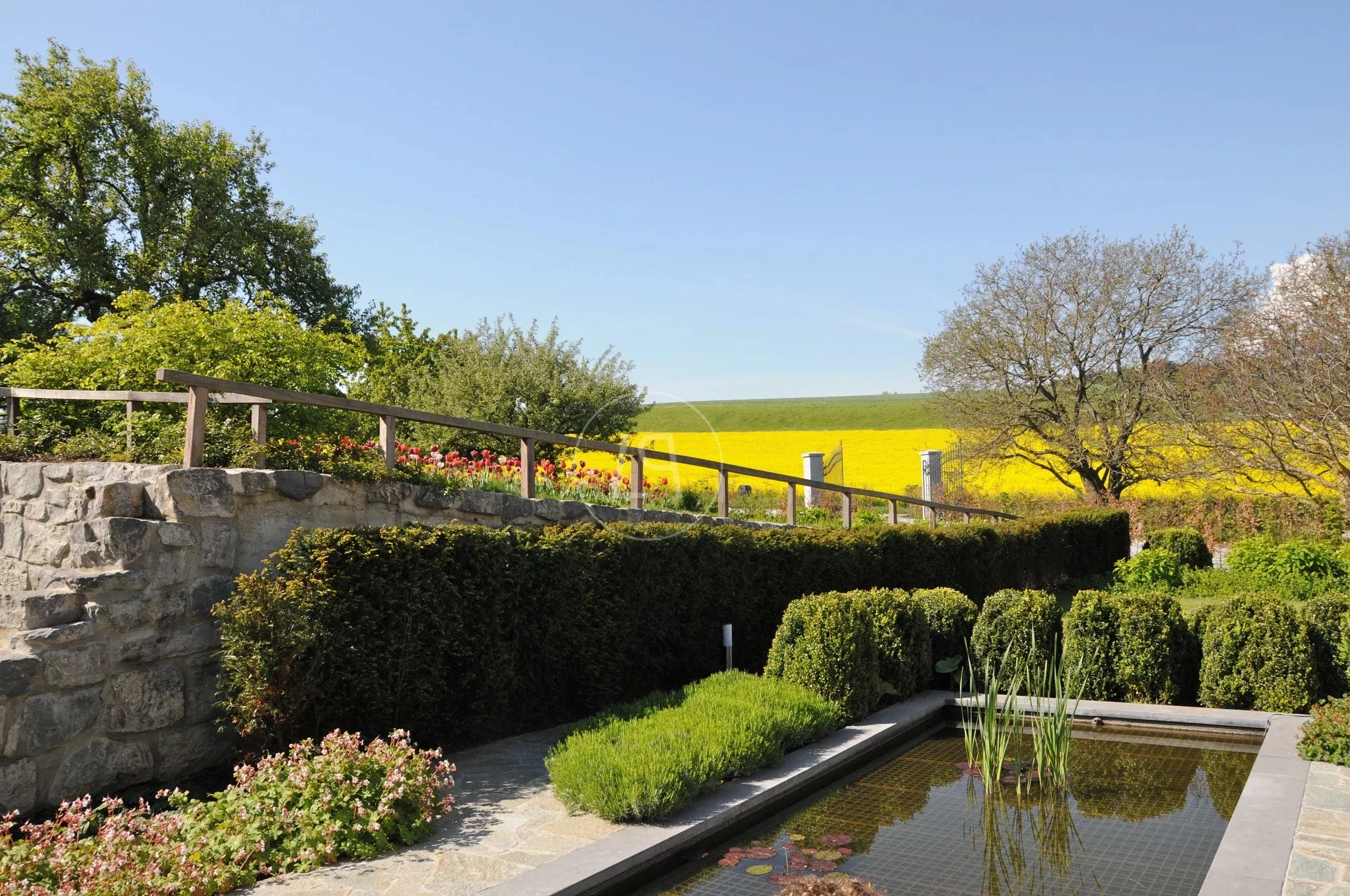 Gartenanlage mit Wasserbecken und Blick über Felder