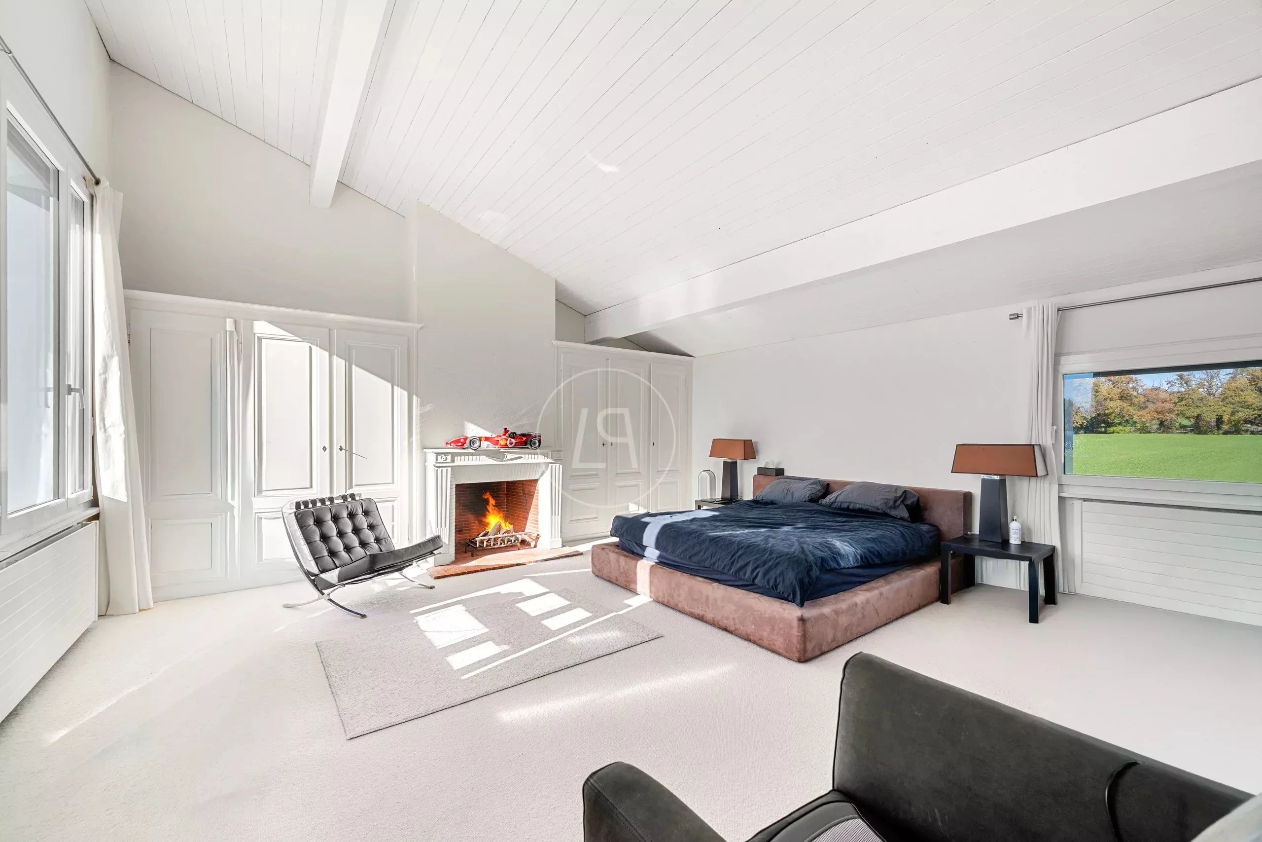 Helles Schlafzimmer mit Kamin und großem Fensterblick