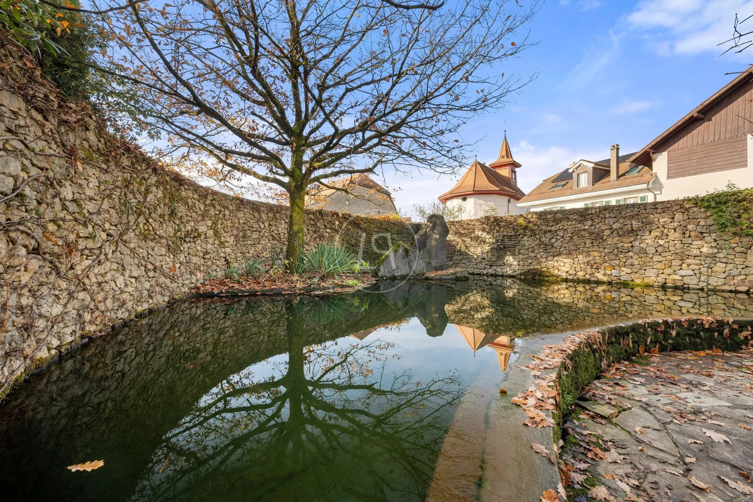 Garten mit Wasserbecken und historischen Häusern