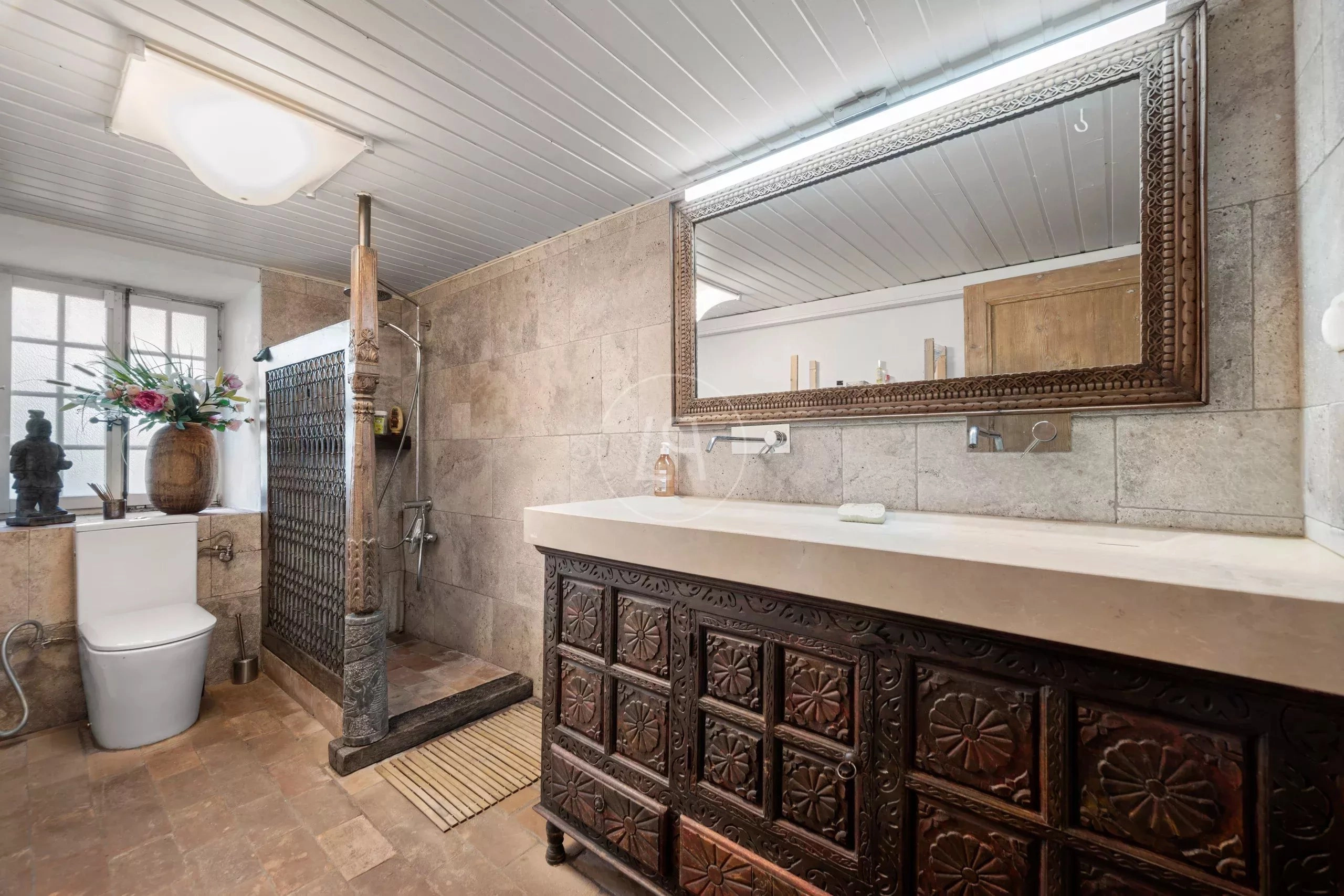 Badezimmer mit Naturstein und geschnitzten Holzmöbeln