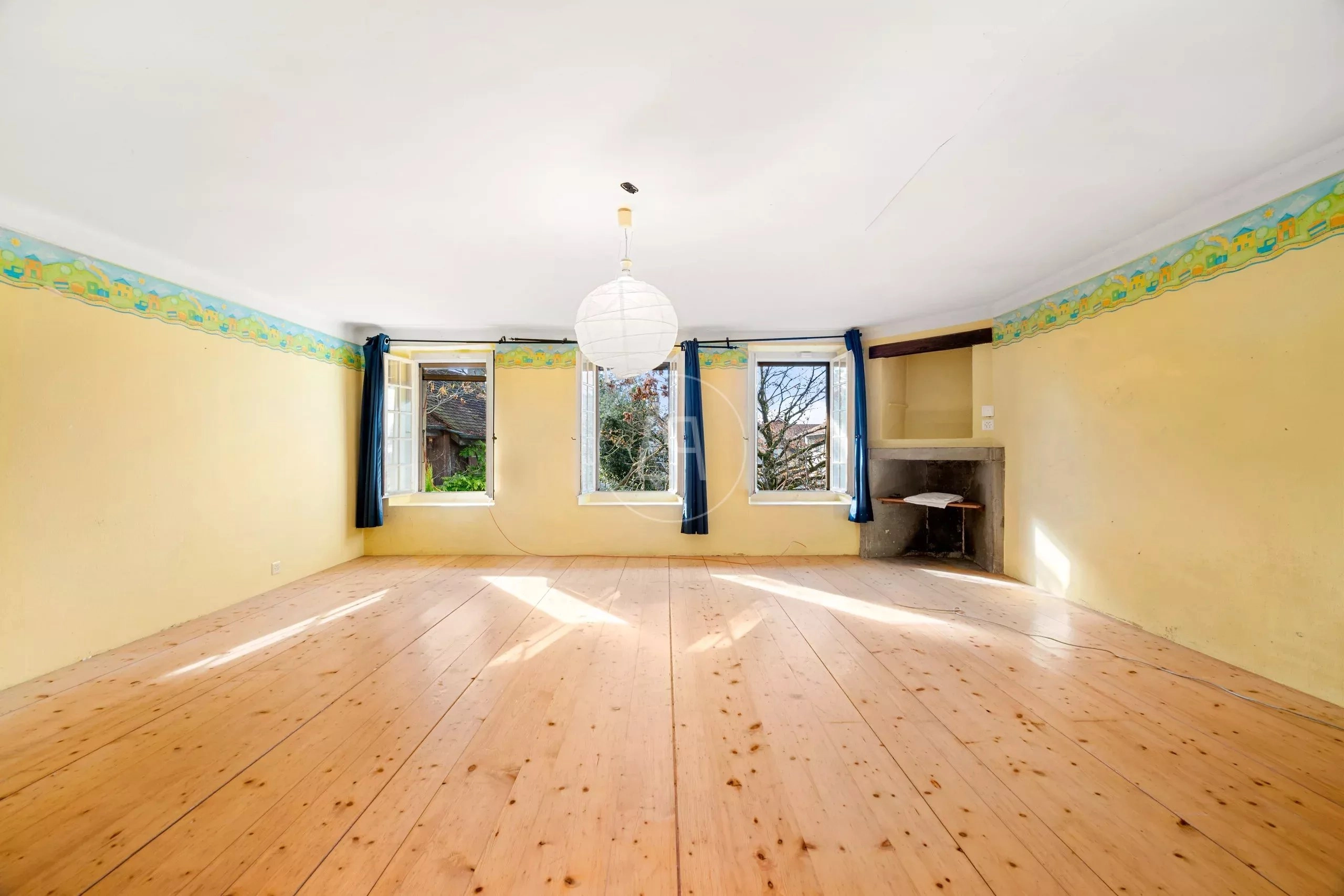 Heller, leerer Wohnraum mit Kamin und Holzdielen