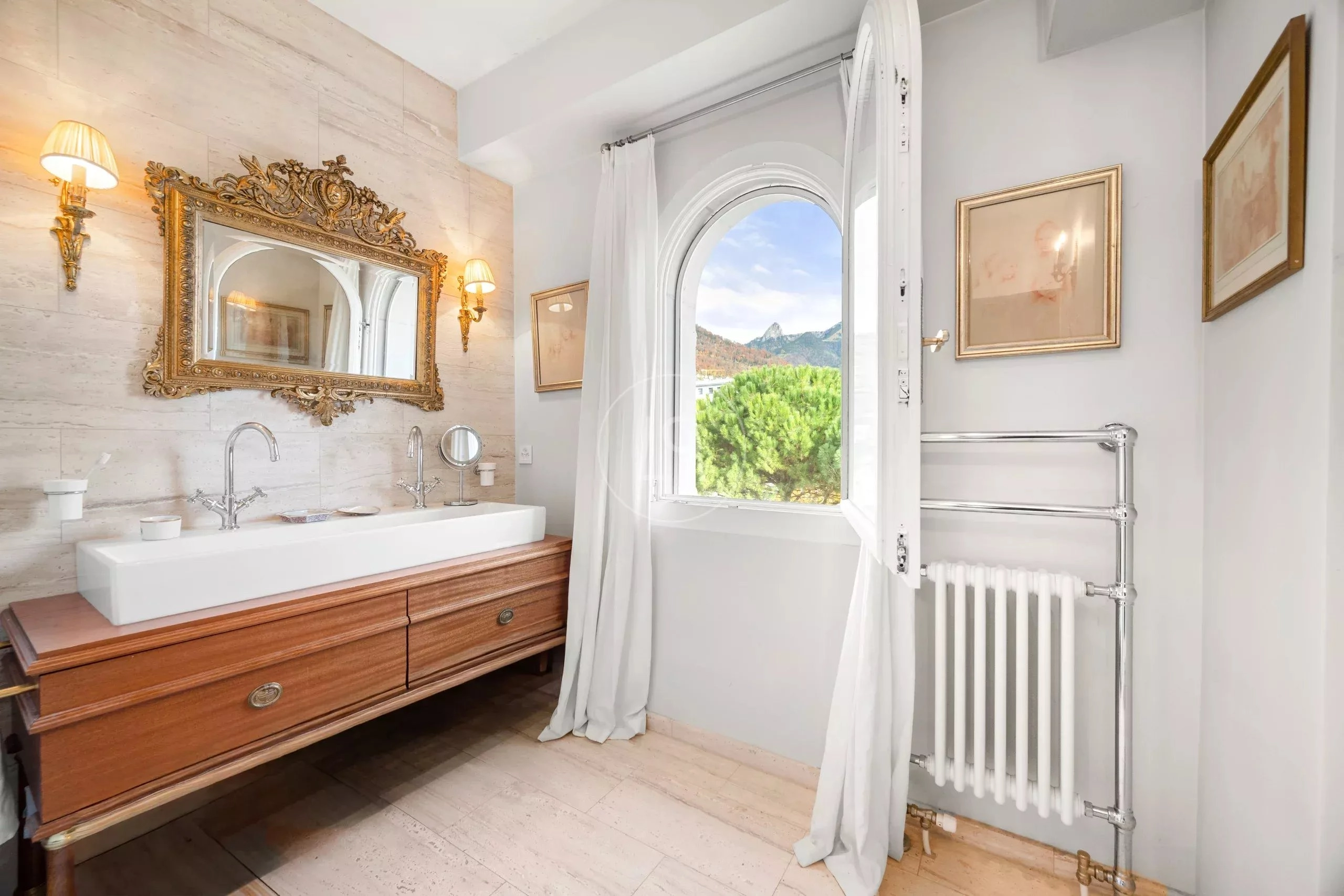 Elegantes Badezimmer mit antikem Spiegel und Blick ins Grüne