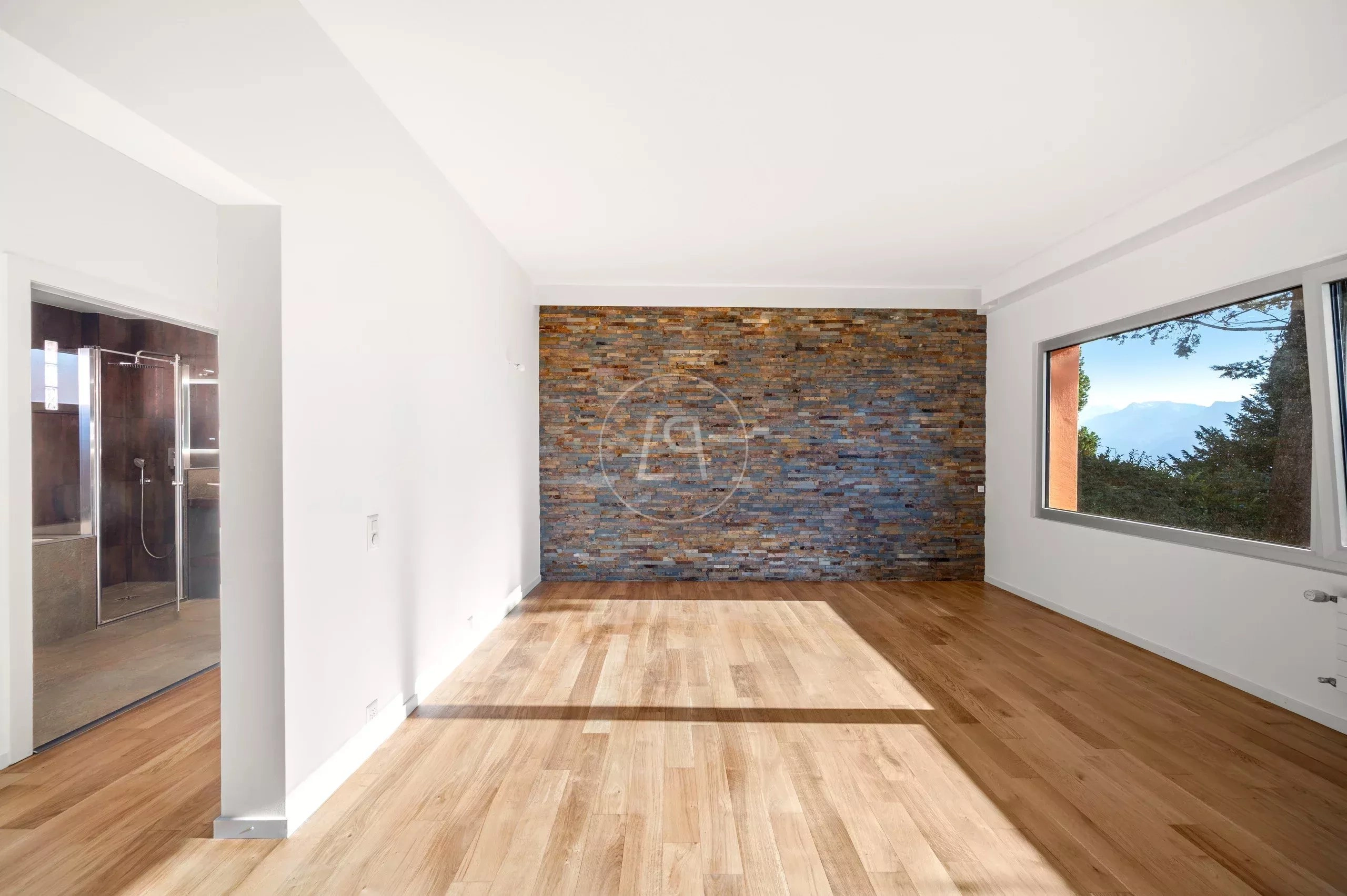 Heller leerer Wohnraum mit Steinakzentwand und Bergblick