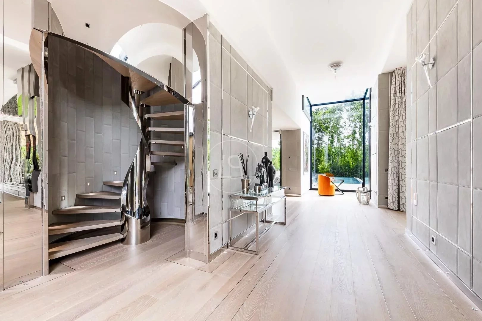 Luxuriöser Eingangsbereich mit Wendeltreppe und Gartenausblick
