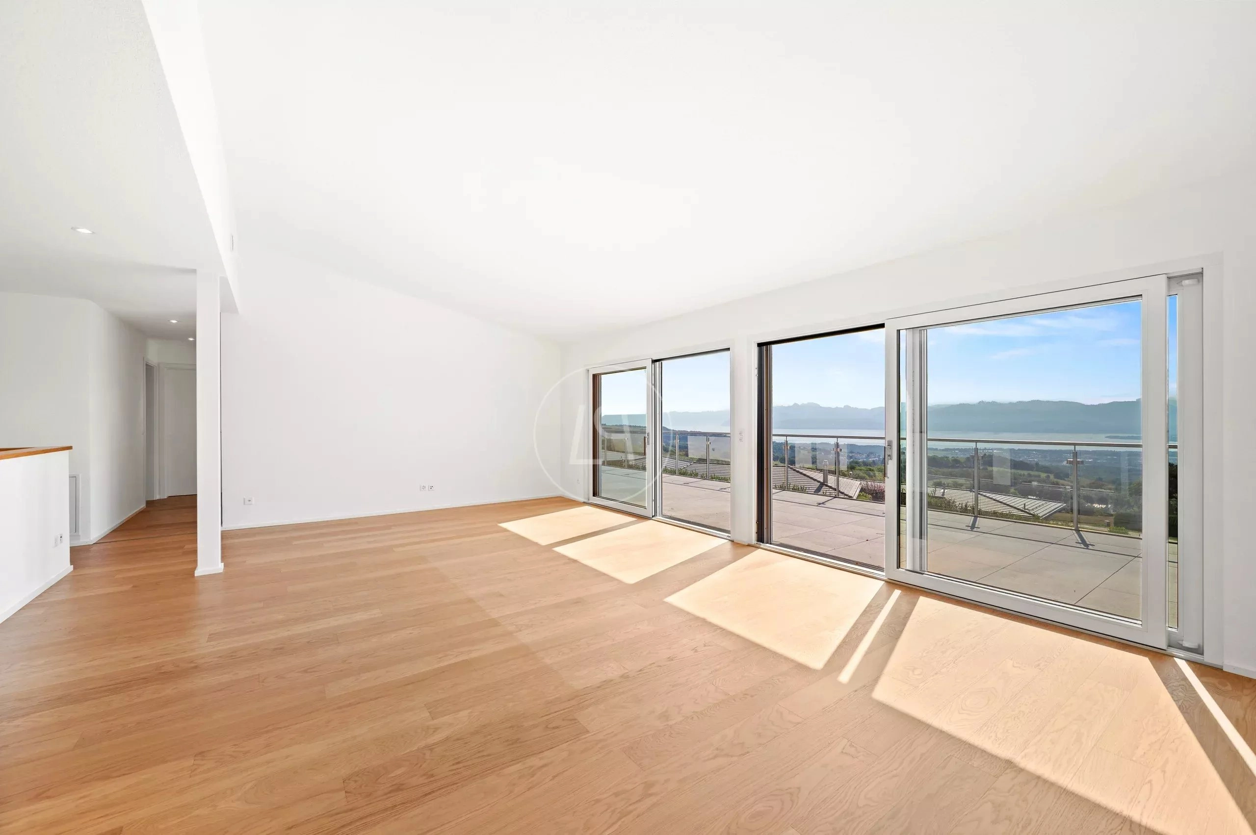 Heller, leerer Wohnraum mit großer Glasfront und Ausblick
