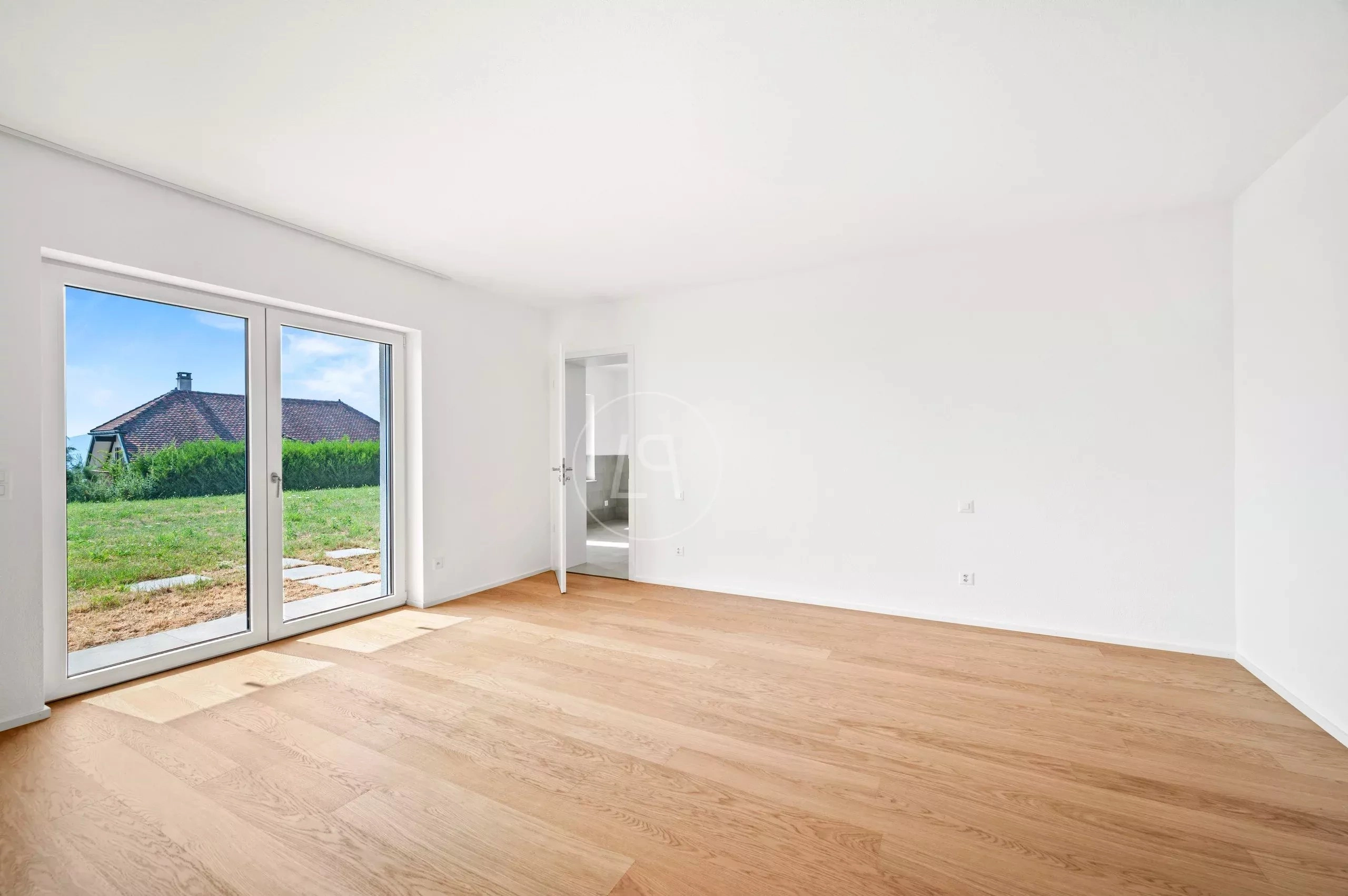 Heller, leerer Wohnraum mit Terrassentür und Gartenblick
