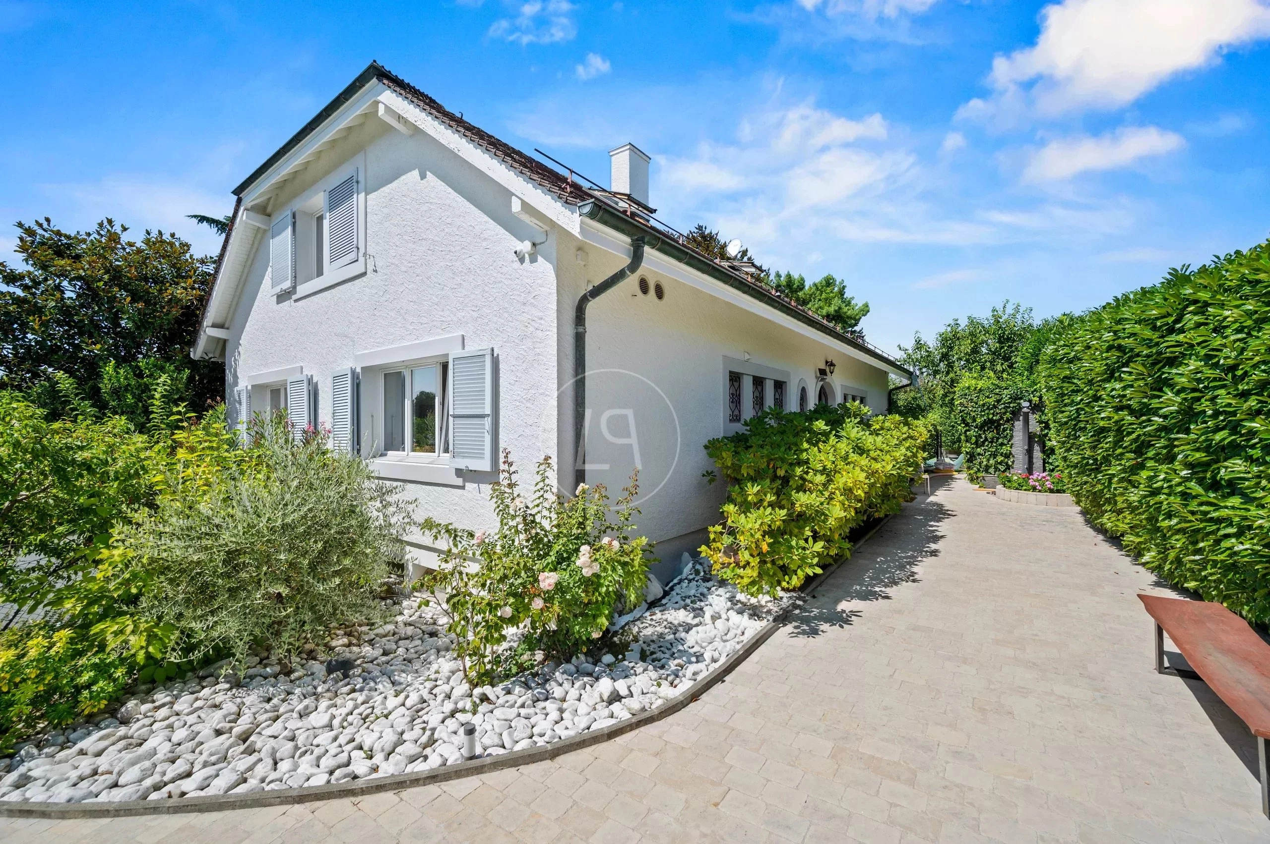 Weiß verputztes Einfamilienhaus mit Gartenweg