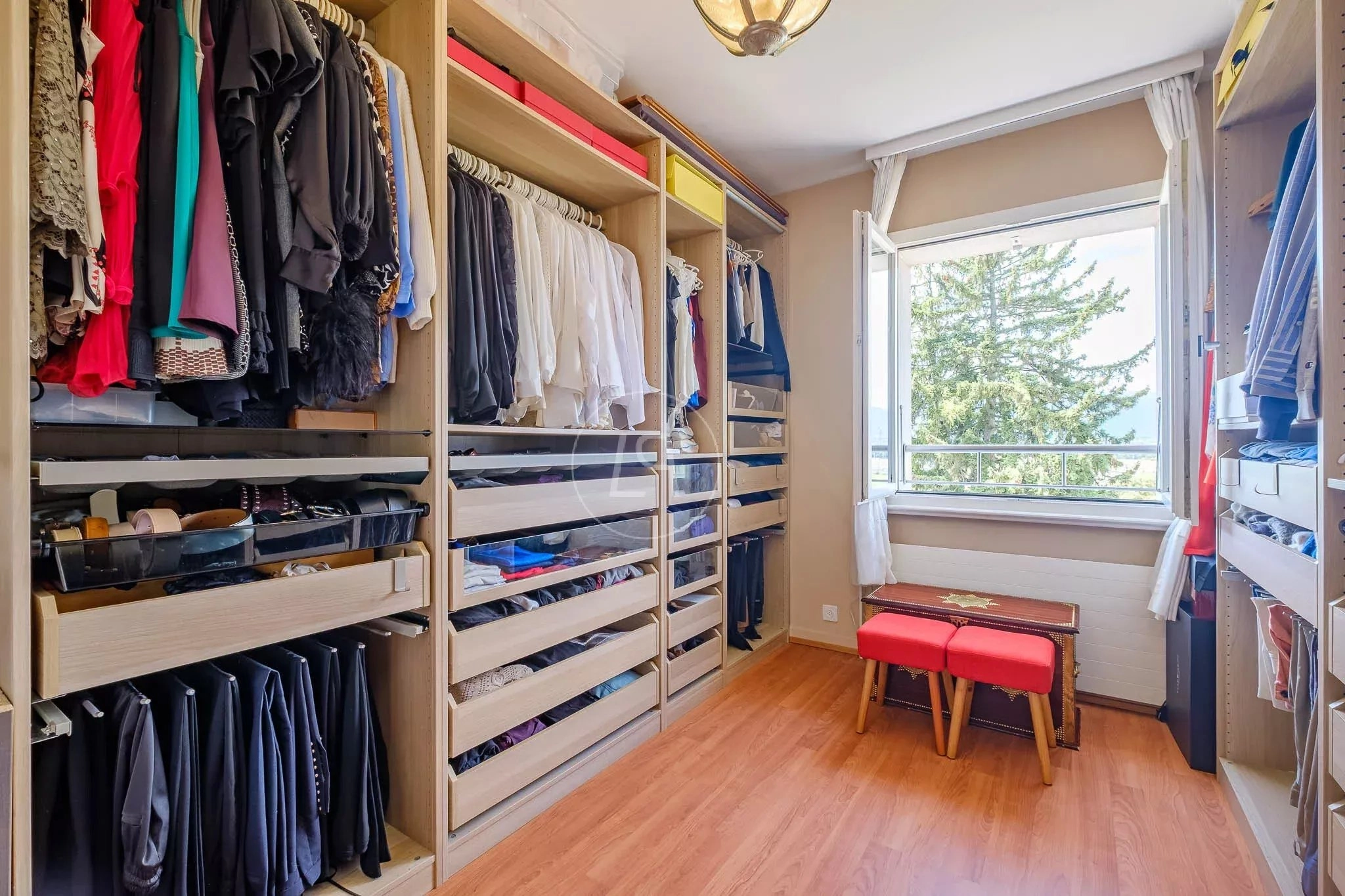 Ankleidezimmer mit offenem Einbausystem und Fensterblick