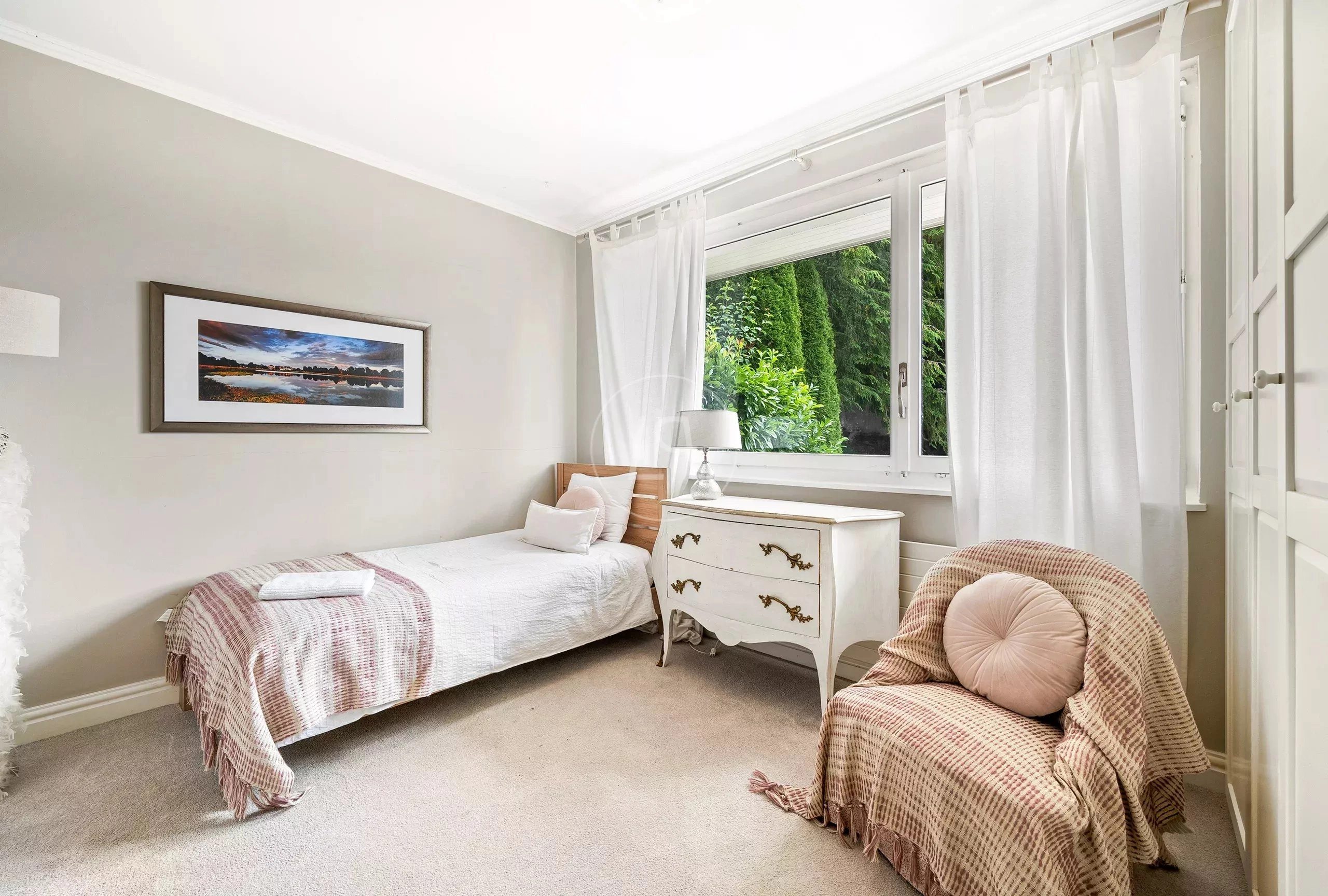 Helles Schlafzimmer mit Einzelbett und Fensterblick ins Grüne