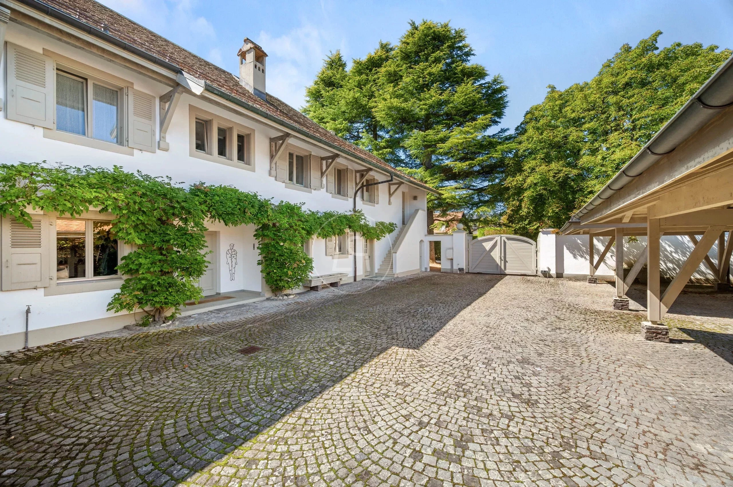 Hof mit weißem Landhaus und Pflasterfläche