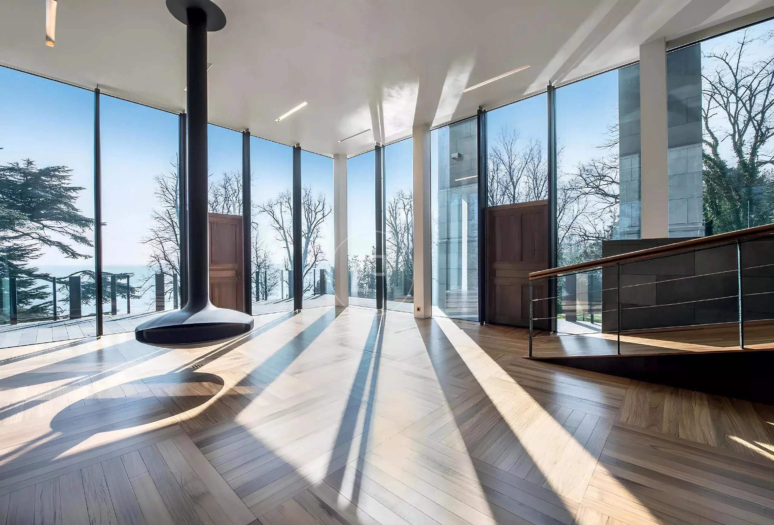 Großzügiger, lichtdurchfluteter Wohnraum mit Panoramaverglasung und Kamin