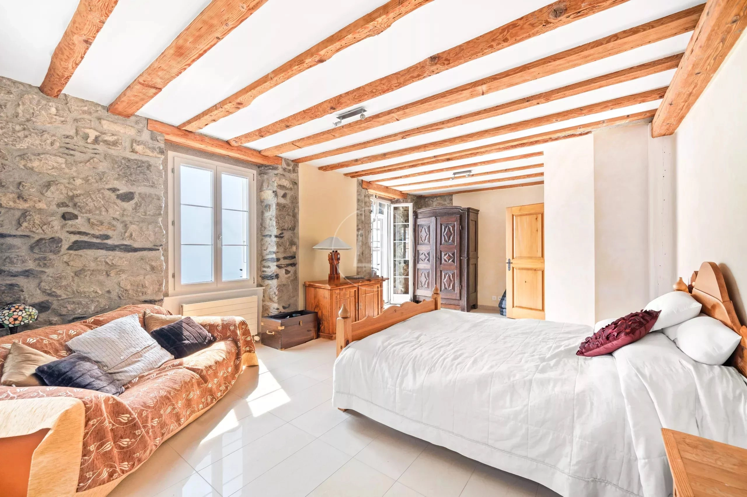 Rustikales Schlafzimmer mit Natursteinwänden und Holzbalkendecke