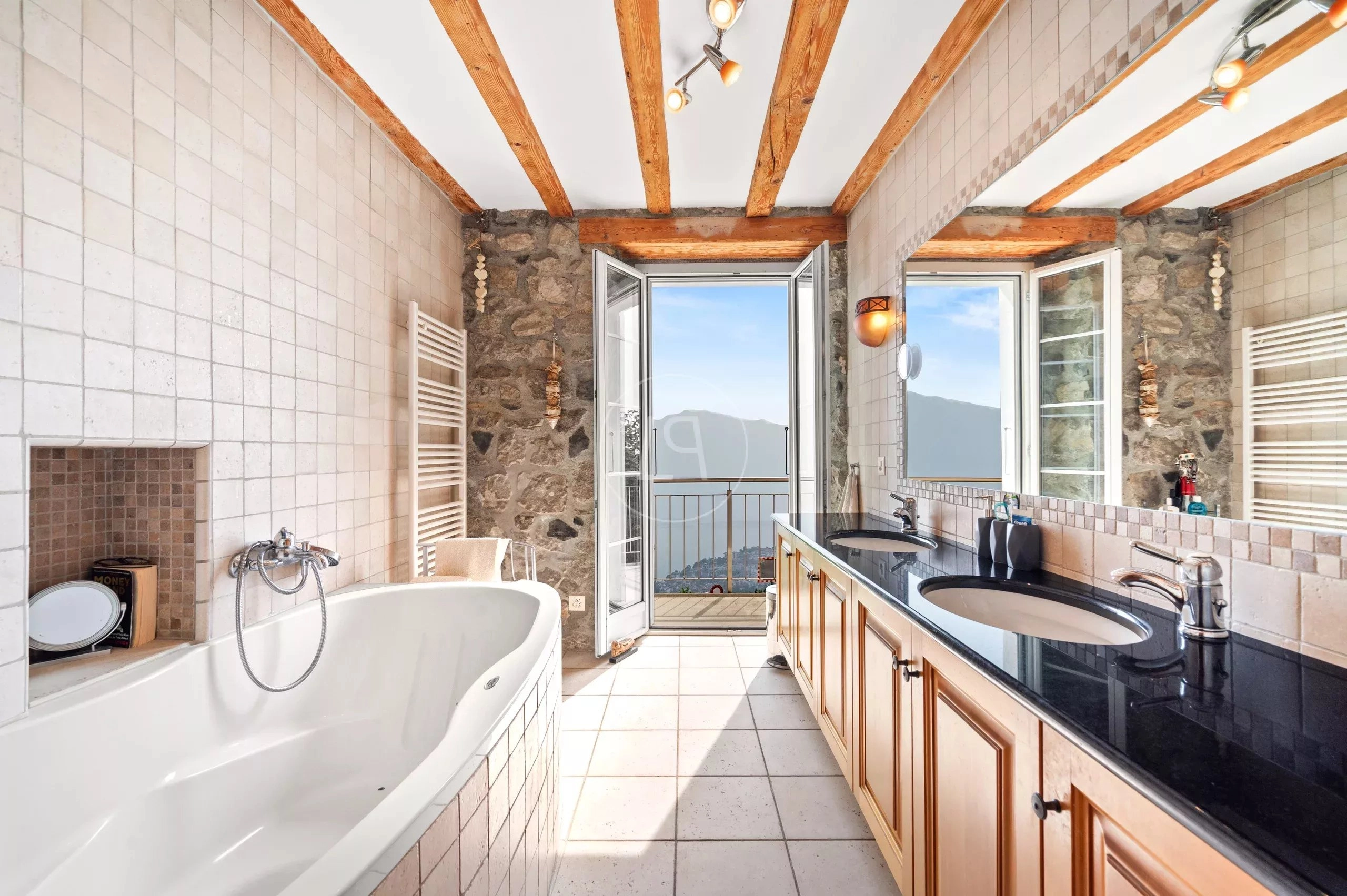 Badezimmer mit Natursteinwand und Balkonblick