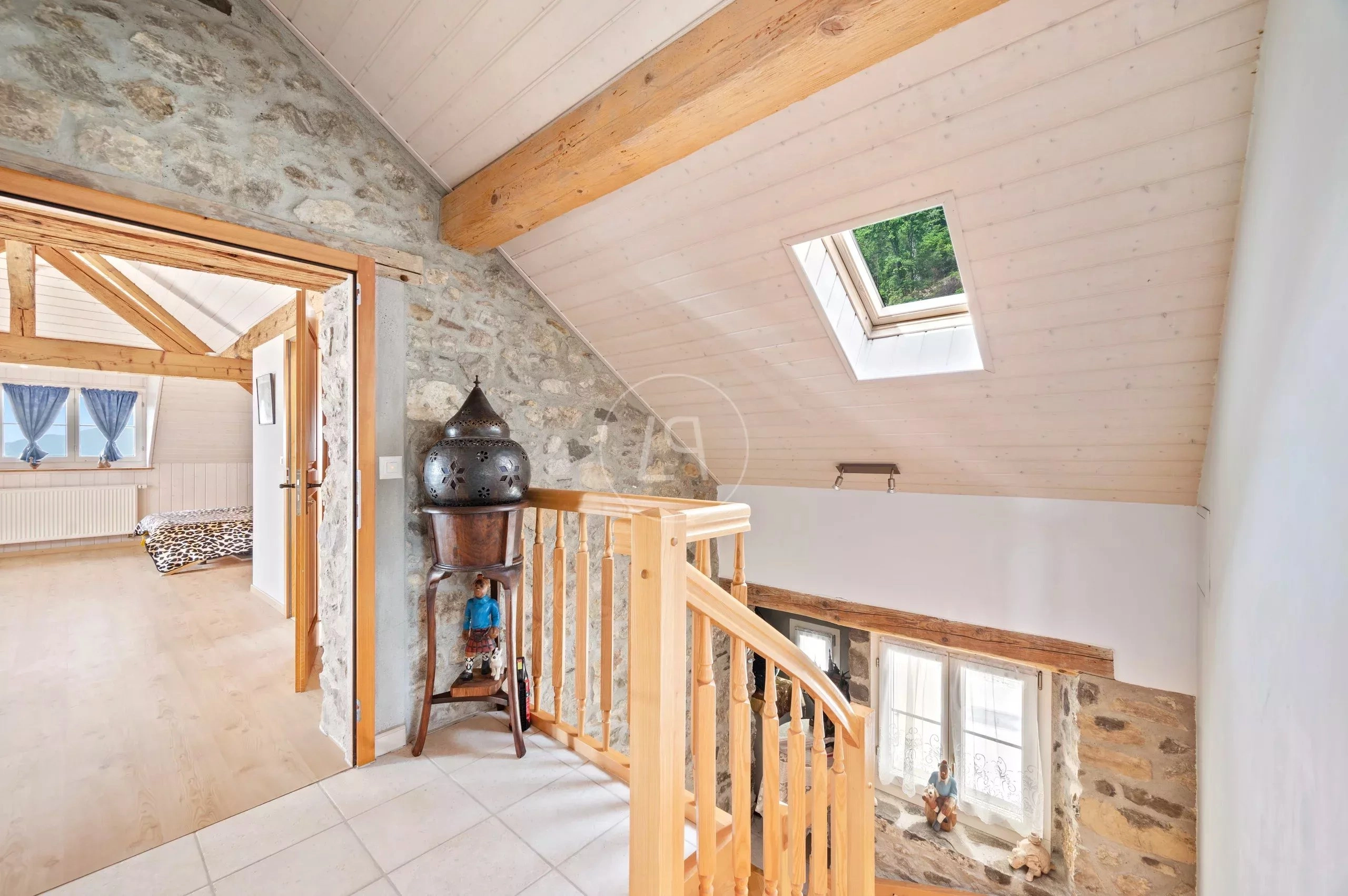Heller Dachgeschossflur mit sichtbaren Holzbalken und Natursteinwand