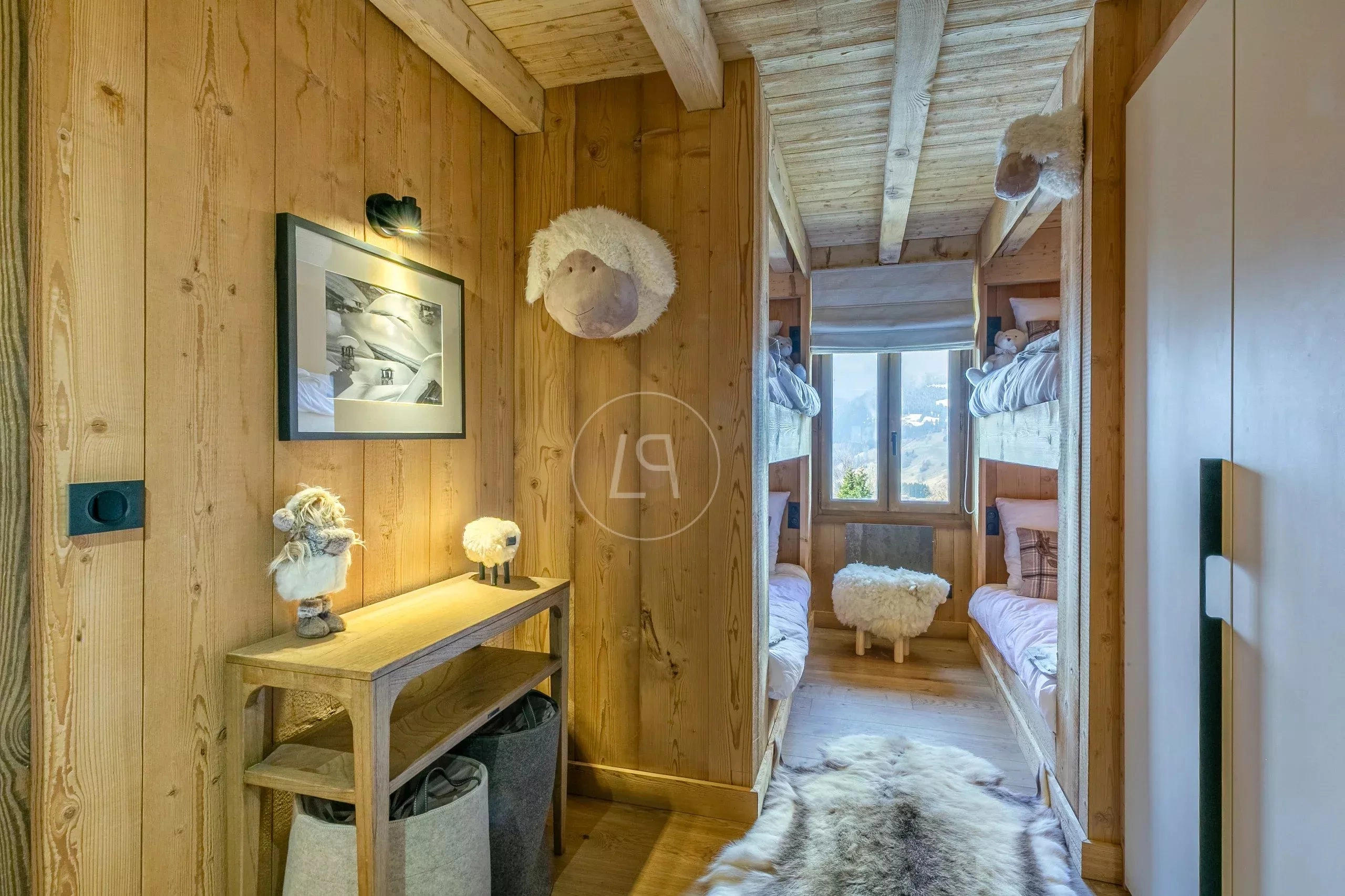 Gemütlicher, holzverkleideter Schlafbereich mit Blick in ein Etagenbett-Zimmer