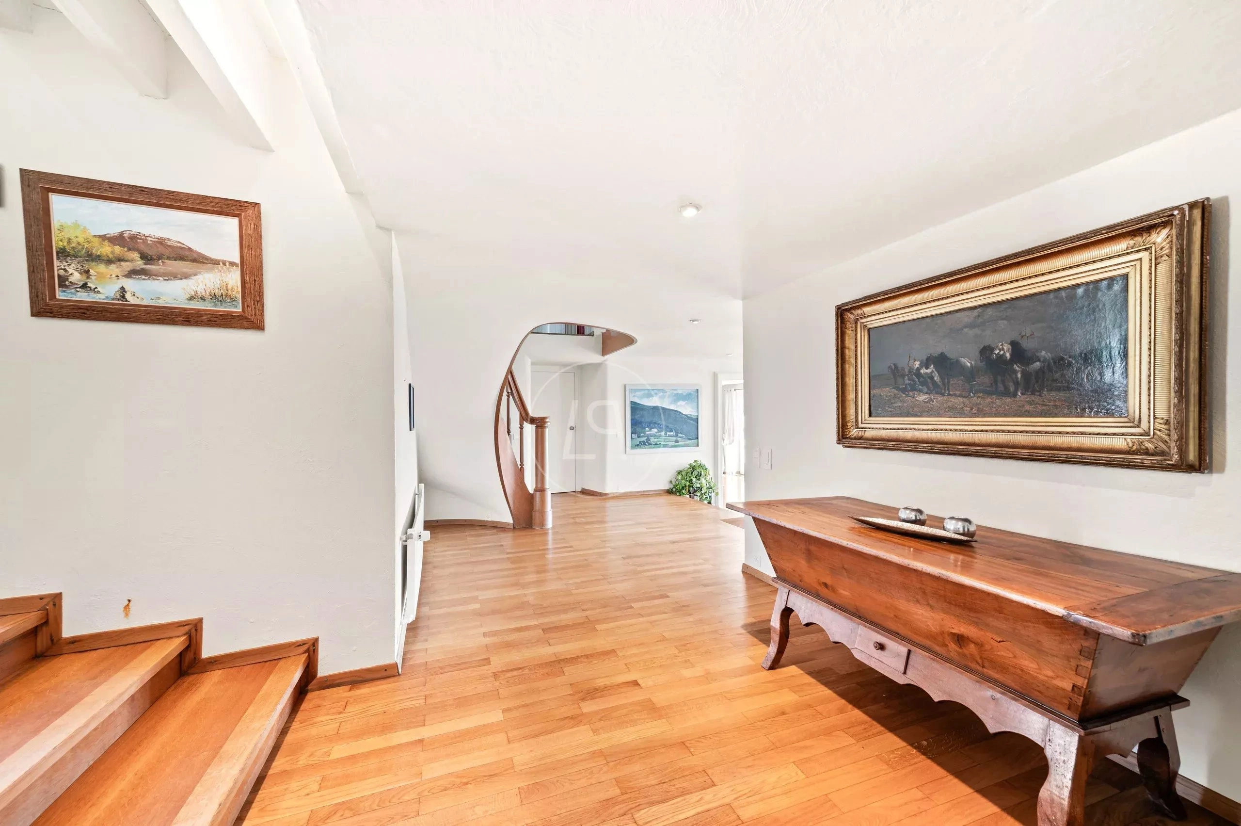 Heller Flur mit Holztreppe und Kunstwerken