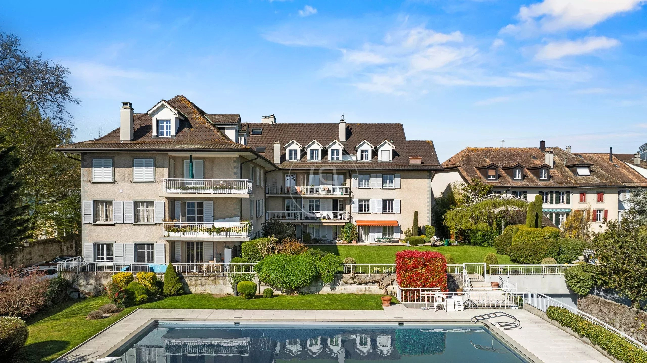Außenansicht einer eleganten Wohnanlage mit Garten und Pool
