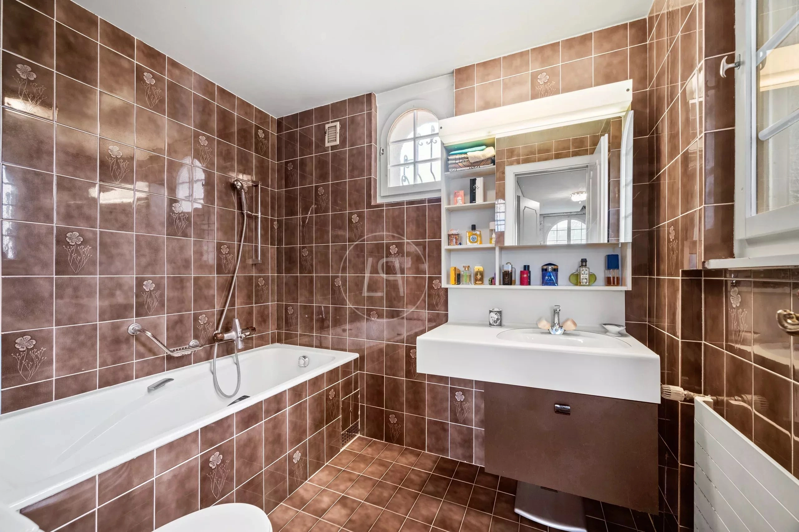 Badezimmer mit braunen Wandfliesen und Badewanne