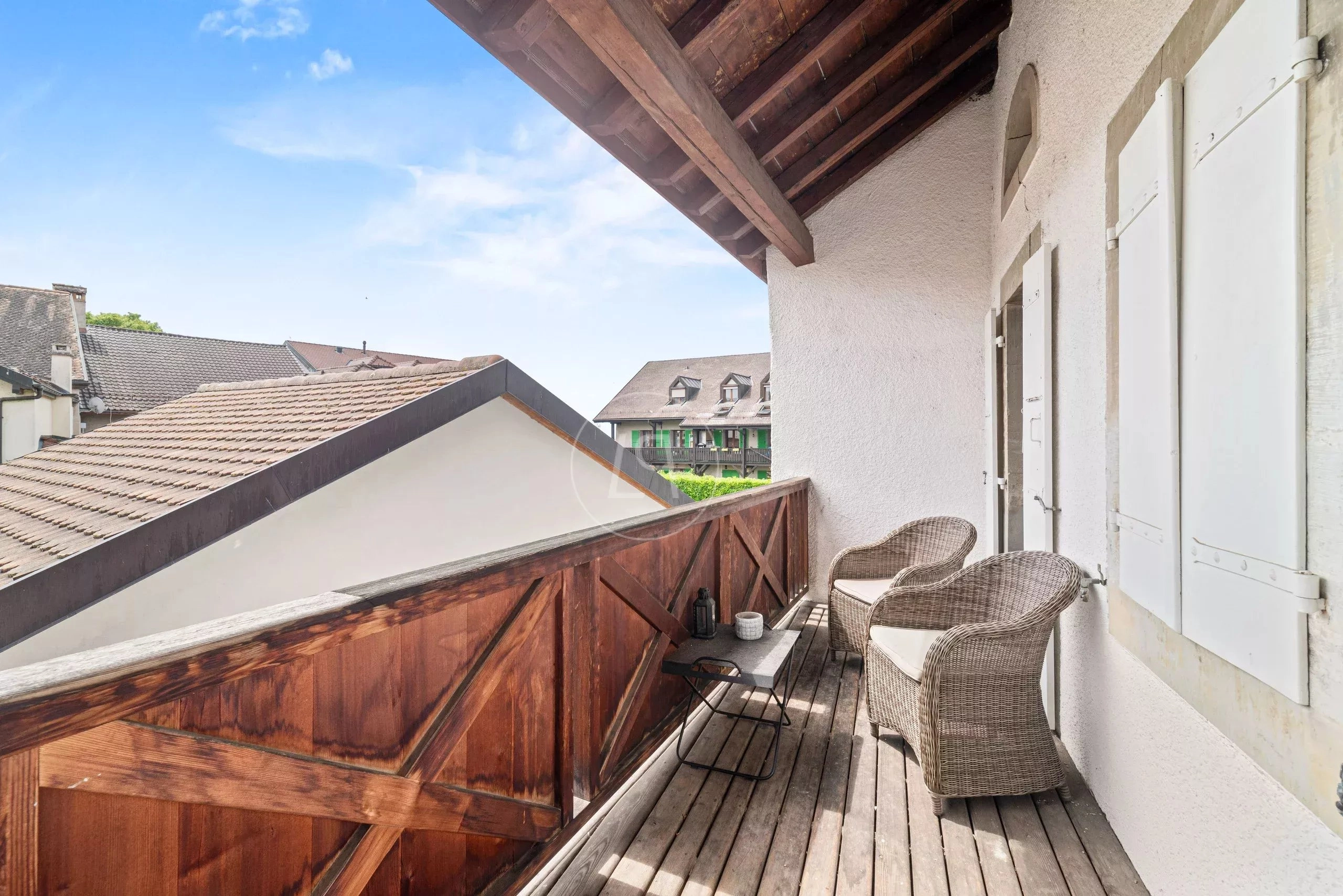 Balkon mit Holzmöbeln und Blick über Dächer