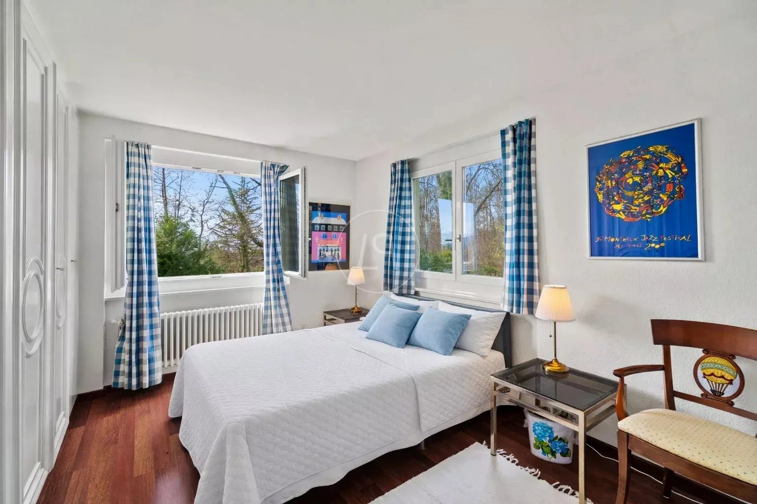 Helles Schlafzimmer mit zwei Fenstern und blau-weißen Vorhängen