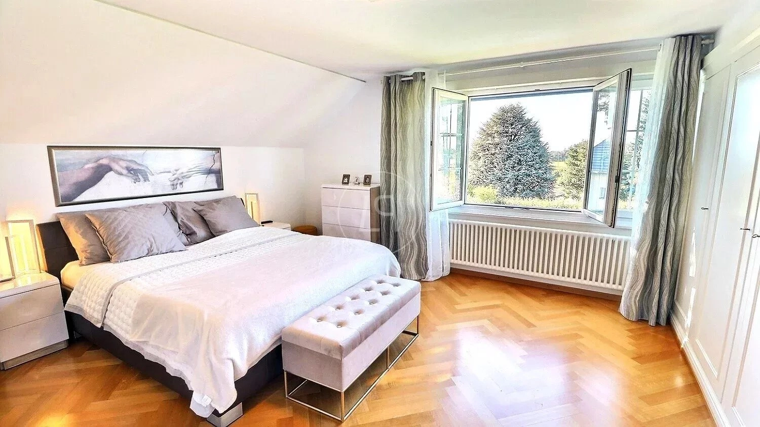 Helles Schlafzimmer mit offenem Fenster und Blick ins Grüne