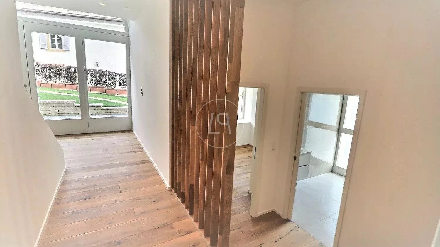 Heller Flur mit Holzlamellen und Zugang zu mehreren Räumen