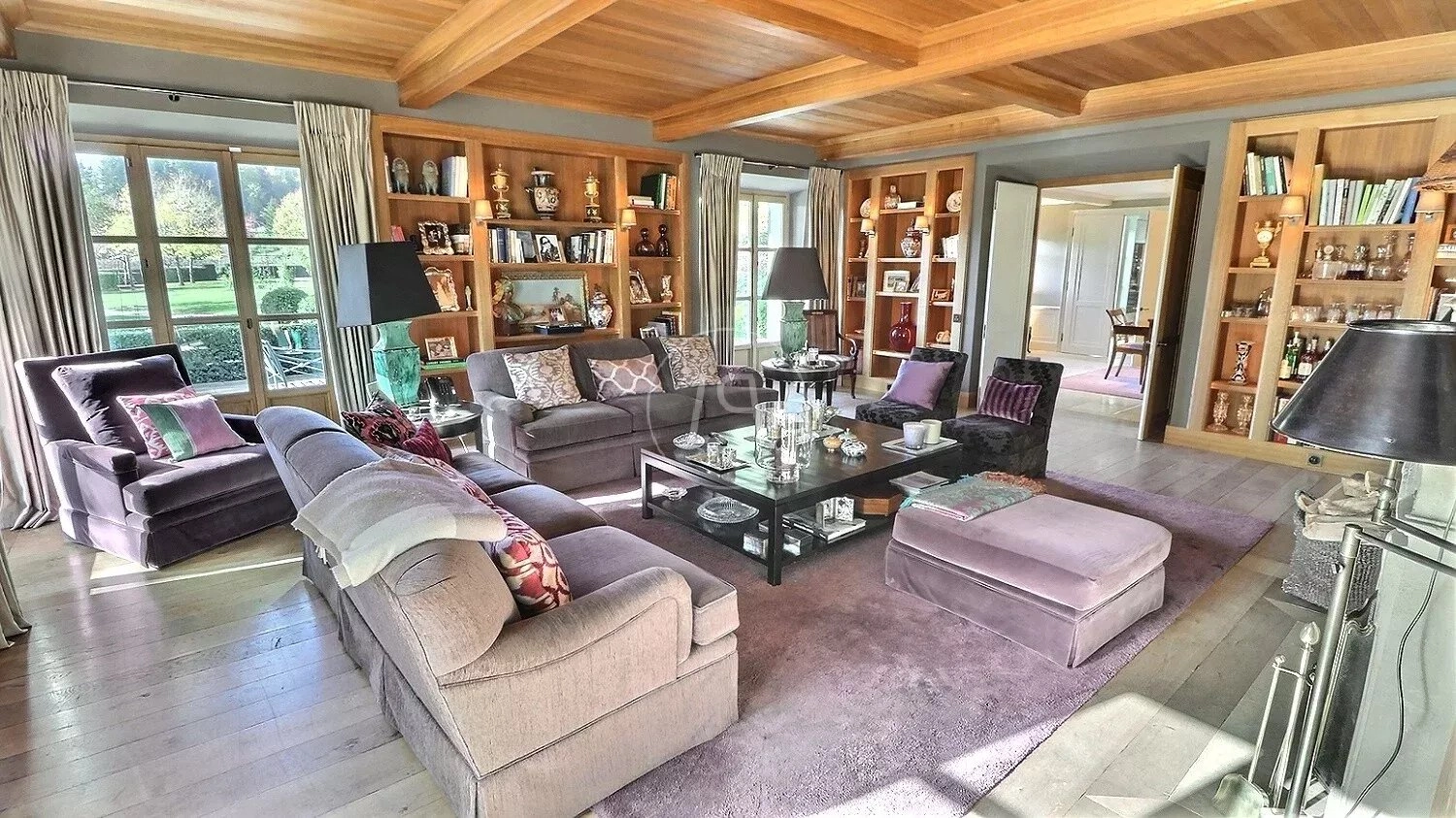 Elegantes Wohnzimmer mit Holzdecke und Blick ins Grüne