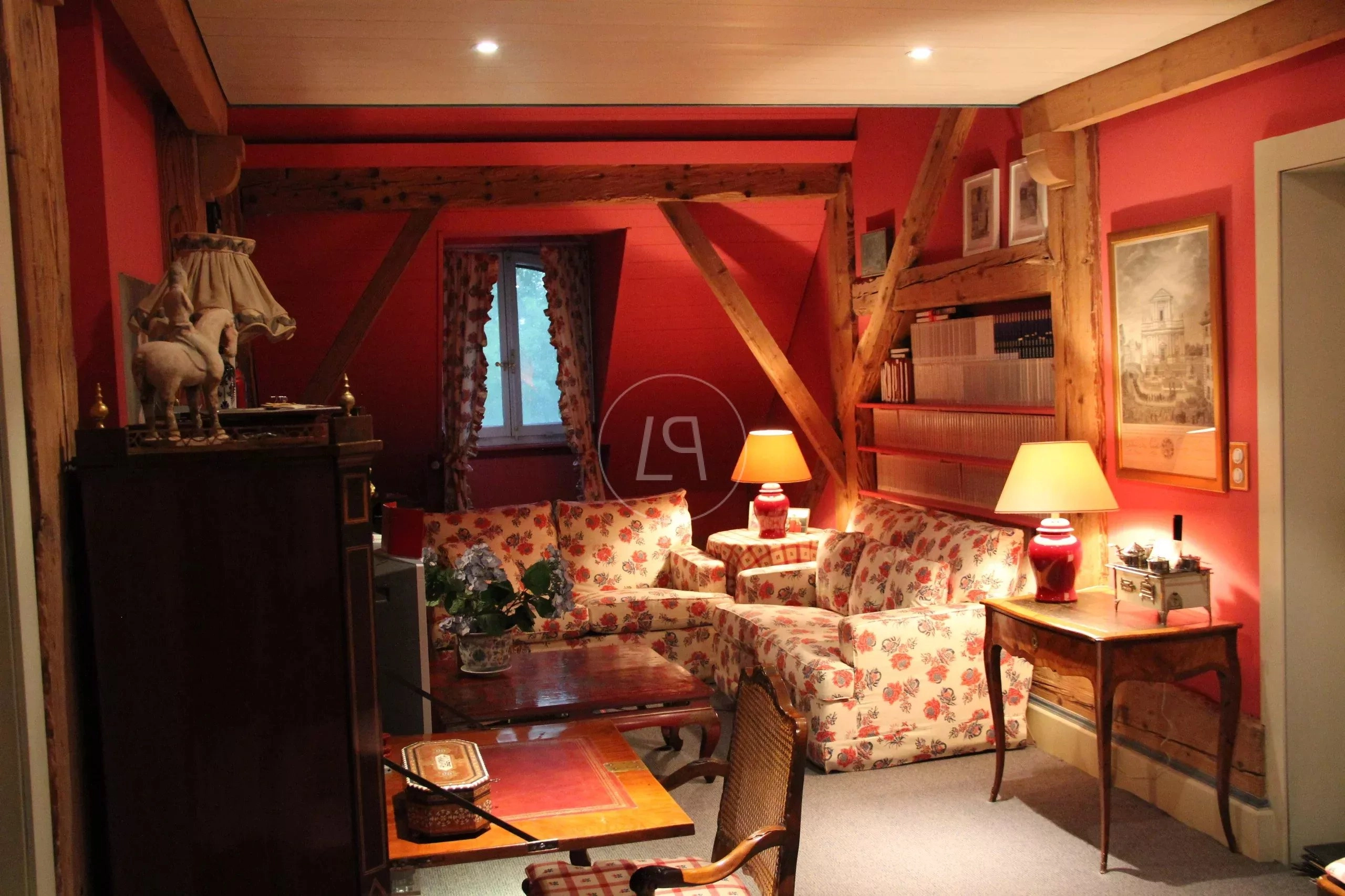 Gemütliches, rustikales Wohnzimmer mit roter Wandfarbe und sichtbaren Holzbalken