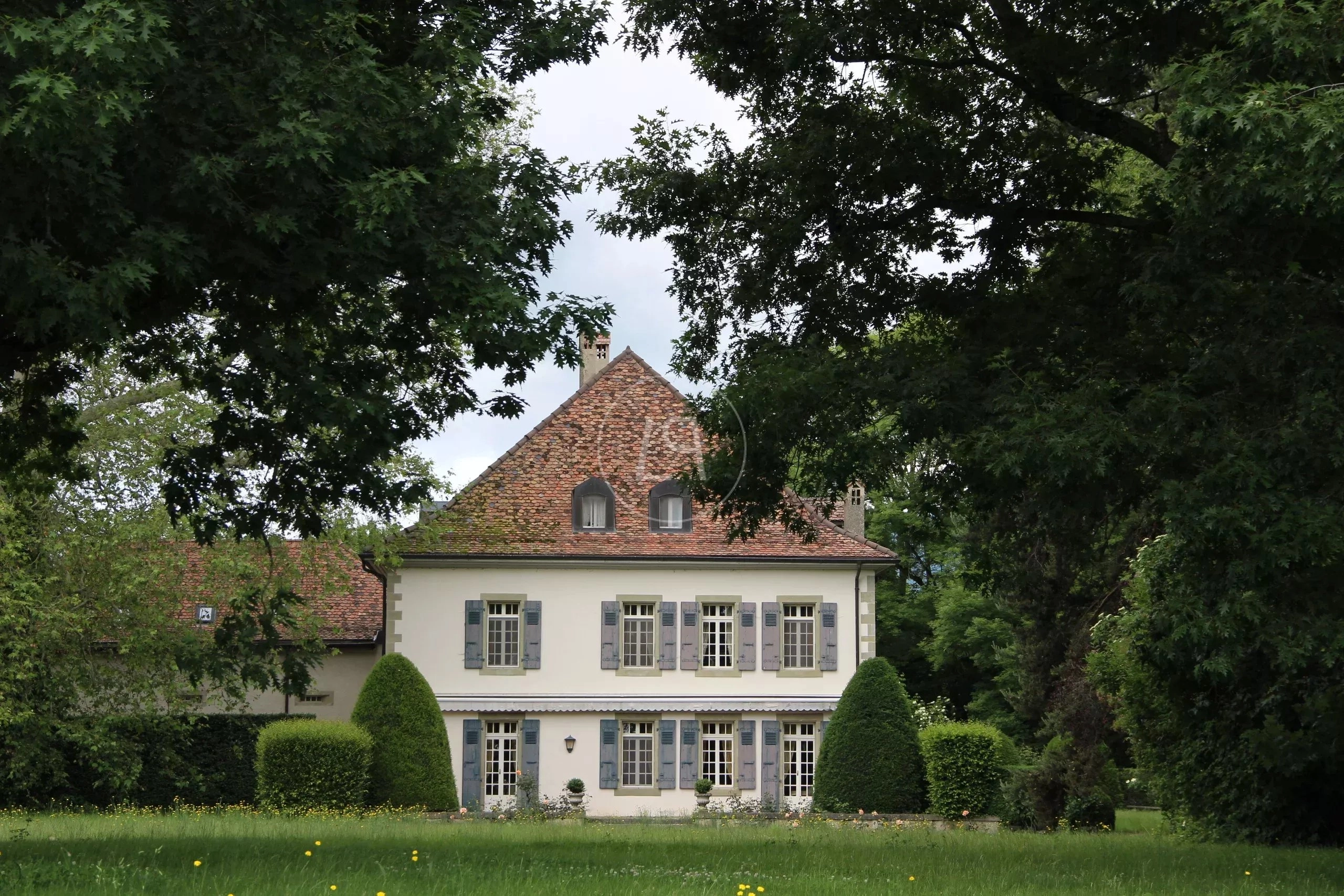 Historisches Landhaus hinter dichtem Baumbestand