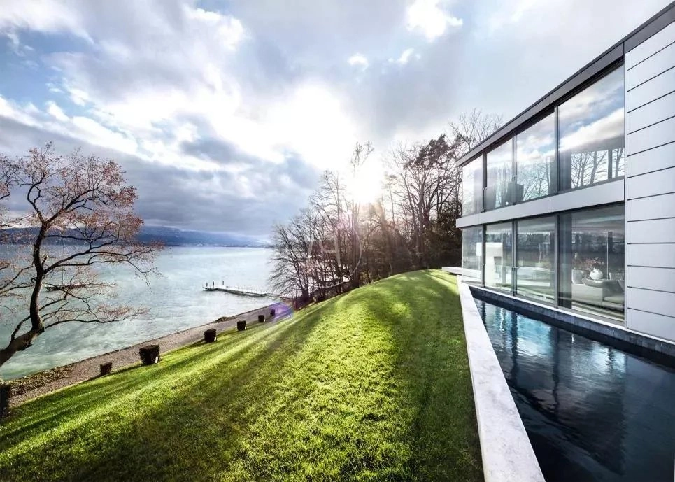 Moderne Villa am See mit großem Glasfront und Ufergarten
