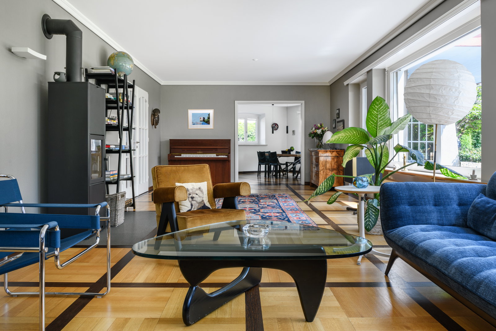 Helles Wohnzimmer mit Ofen und großen Fenstern