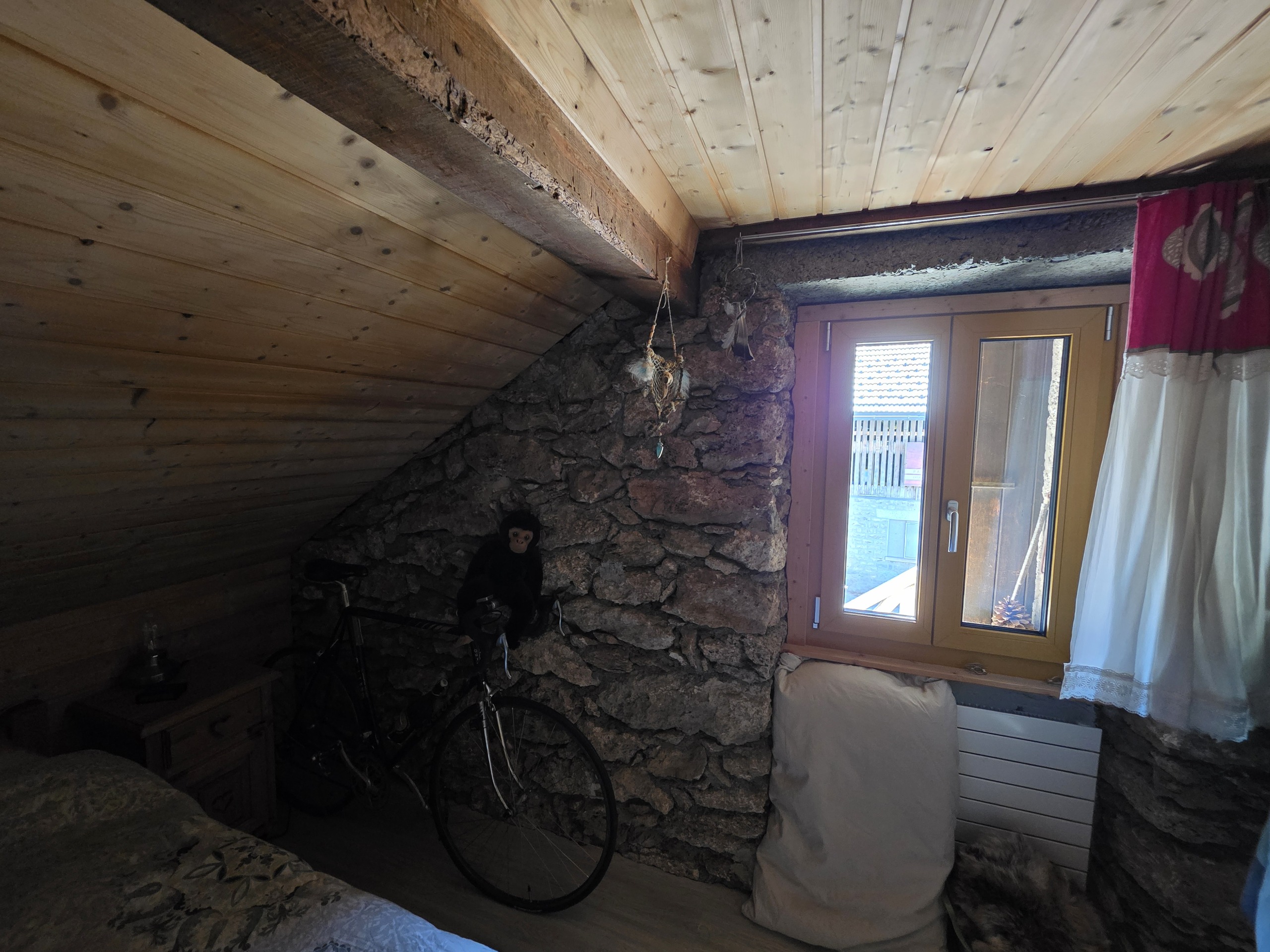 Dachgeschosszimmer mit Natursteinwand und Holzdecke