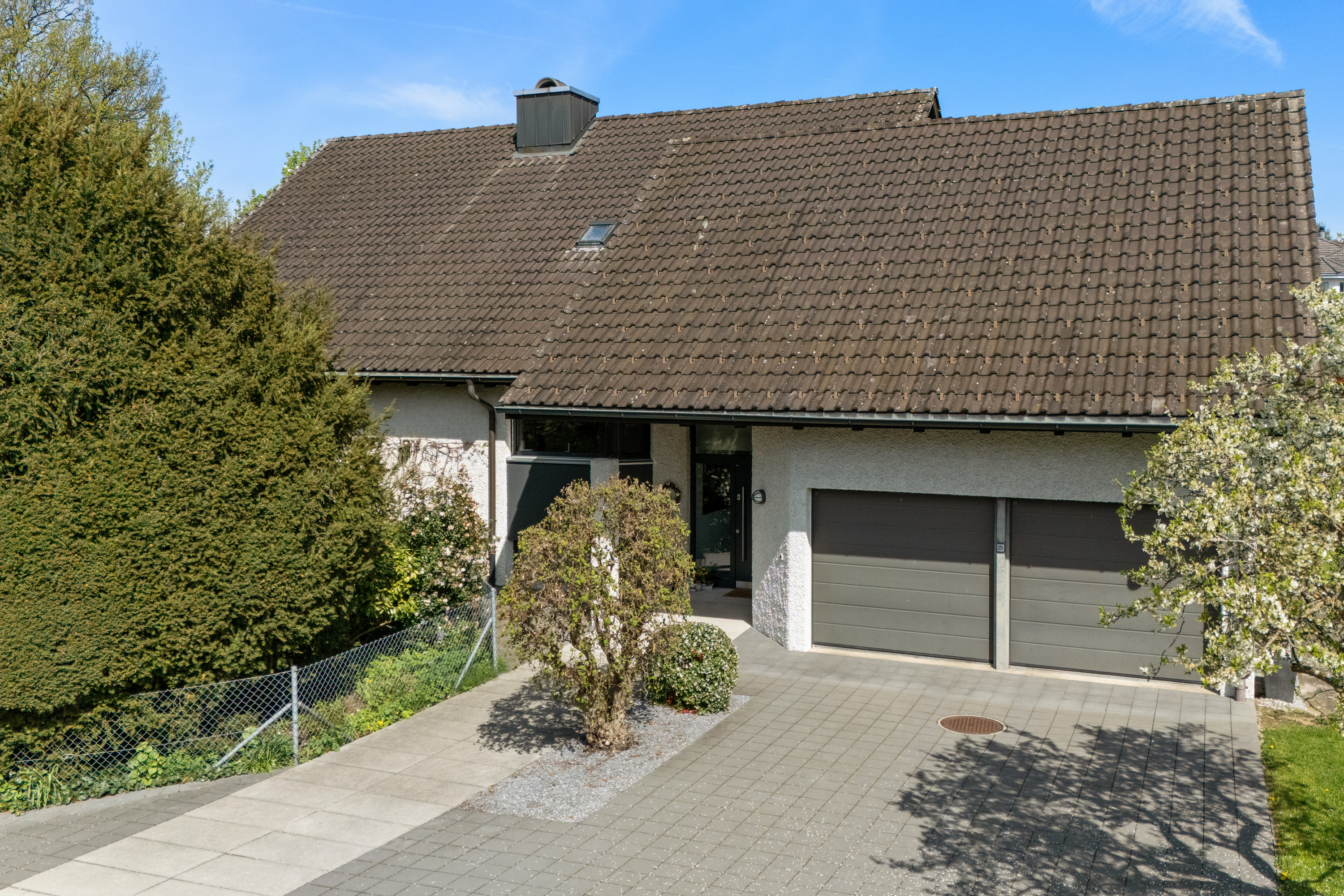 Ein Einfamilienhaus mit großem Satteldach, Doppelgarage und gepflasterter Einfahrt.