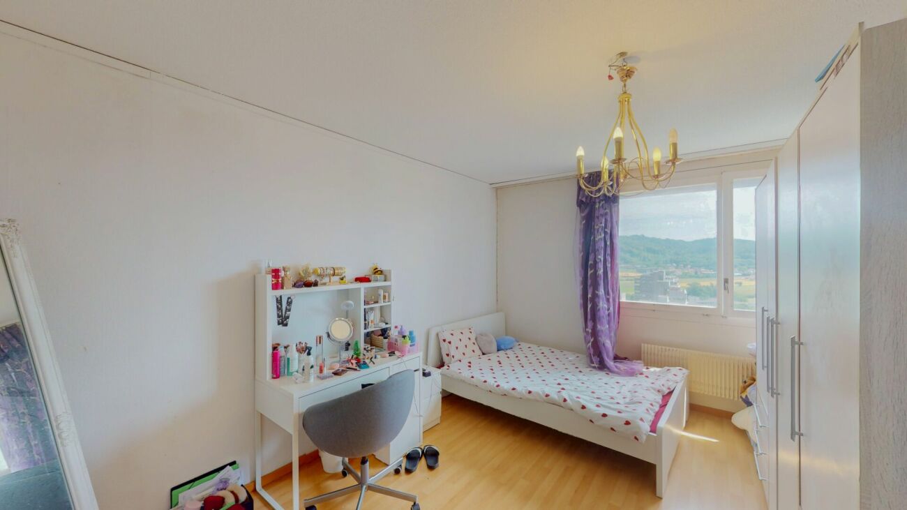 Helles Schlafzimmer mit Schreibtisch und großem Fenster