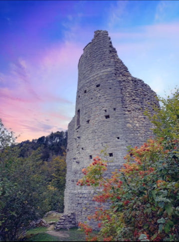 Historischer Steinturm in hügeliger Landschaft bei Sonnenuntergang