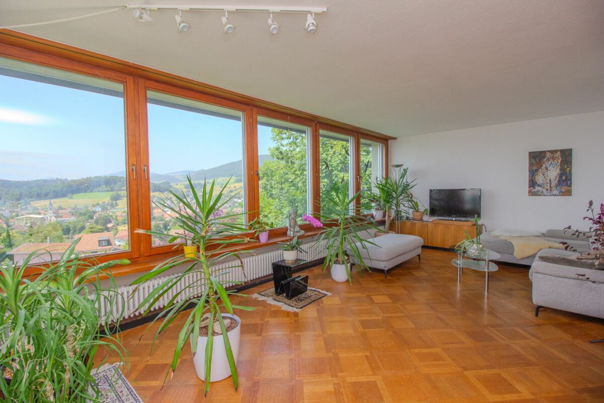 Heller Wohnraum mit Panoramafenstern und Blick ins Grüne