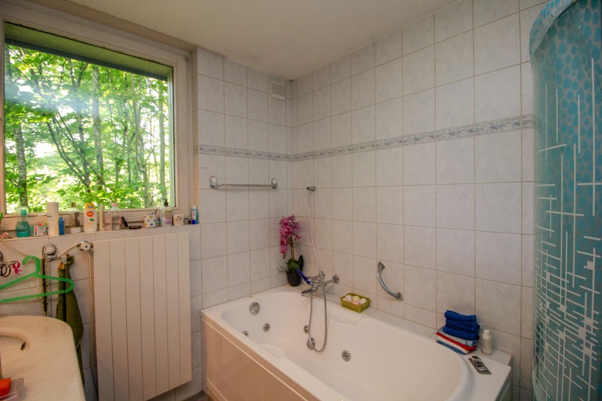 Badezimmer mit Badewanne und Fensterblick ins Grüne