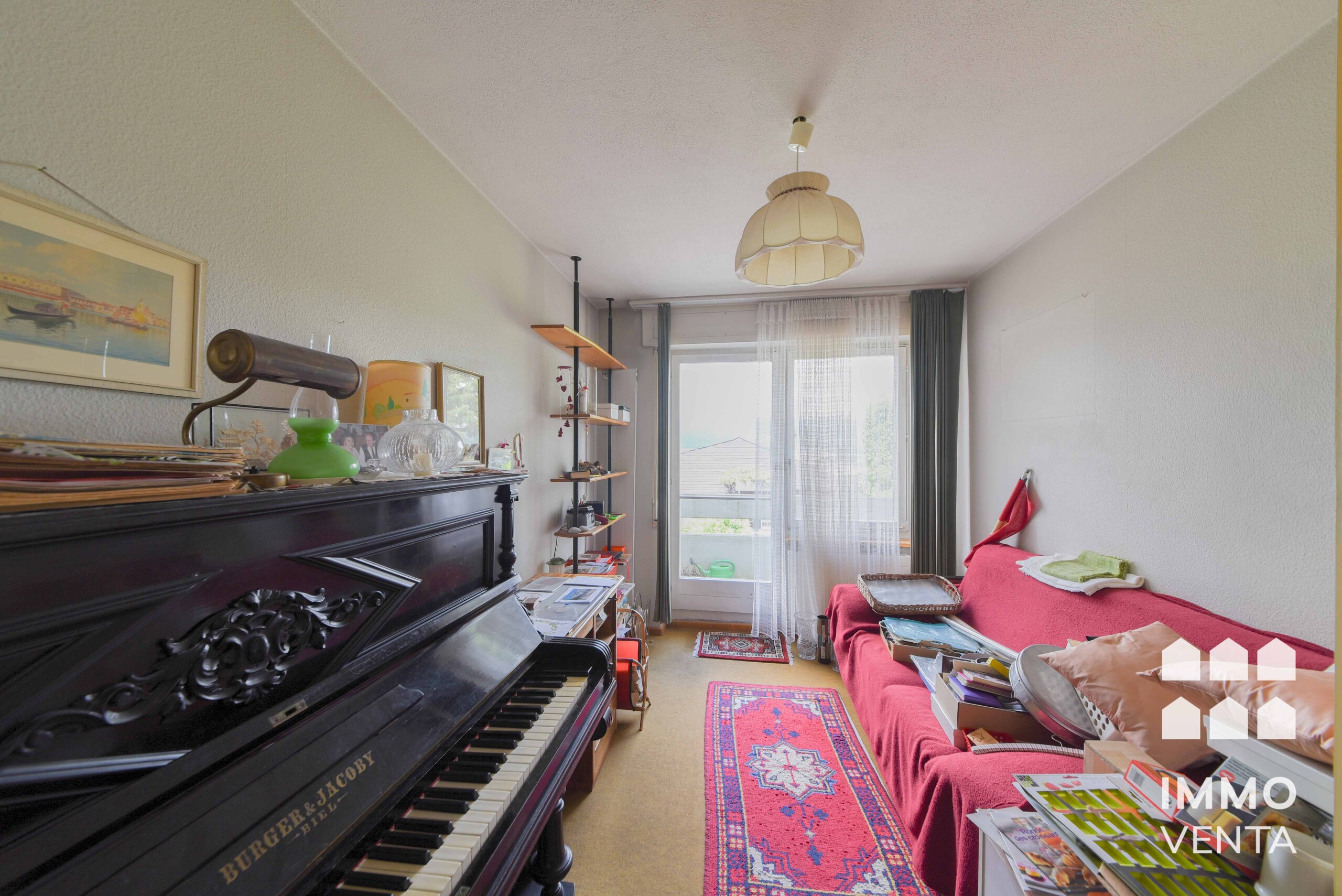 Gemütliches Wohnzimmer mit Klavier und Balkonzugang
