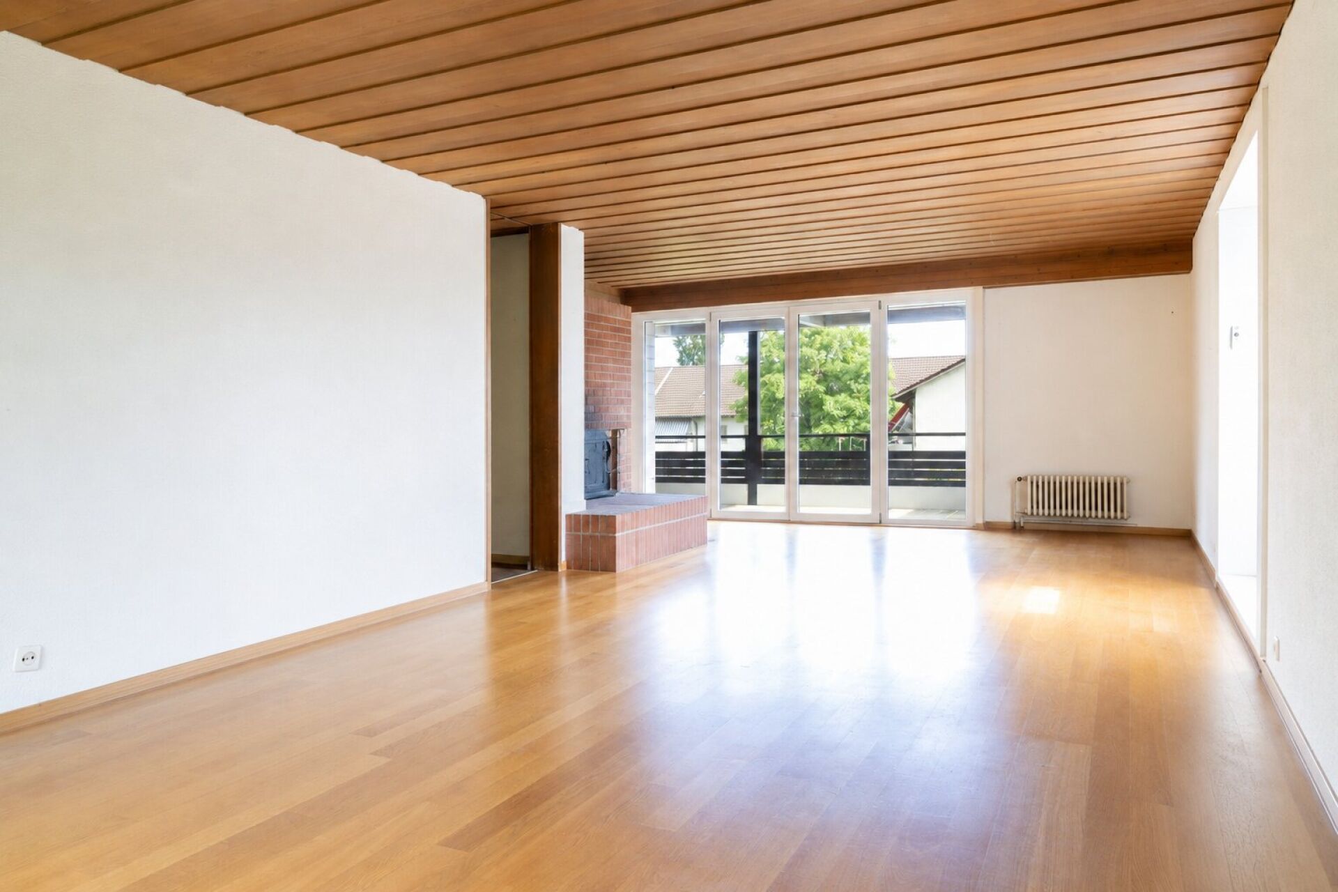 Heller Wohnraum mit Holzdecke und Balkonblick