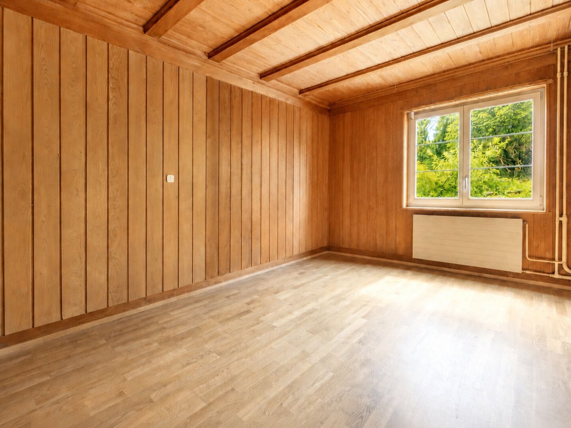 Leerer, holzvertäfelter Raum mit Fenster und Heizkörper