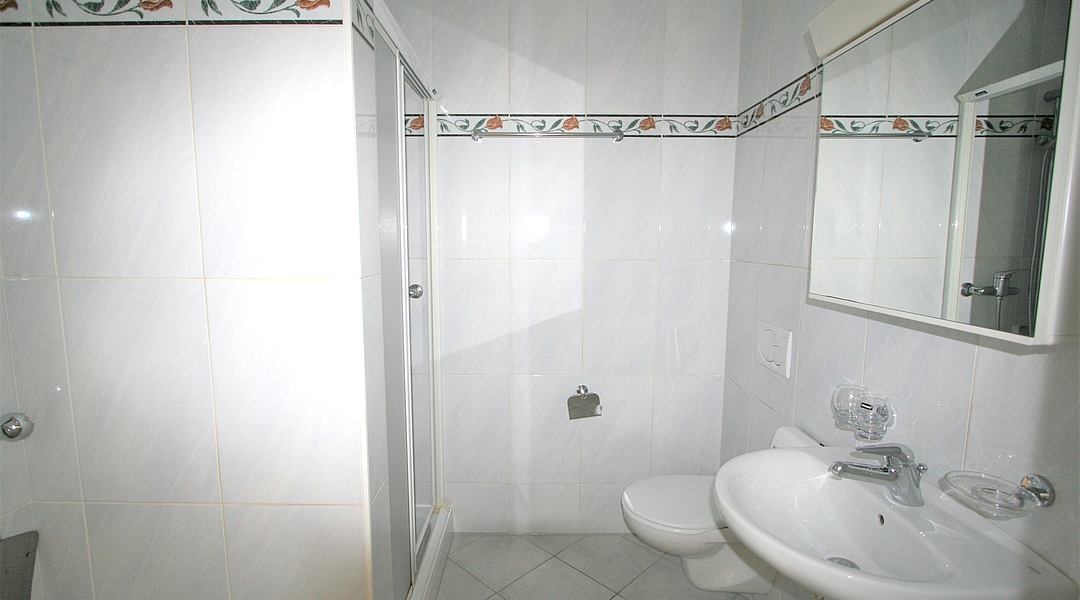 Kleines weißes Badezimmer mit Dusche und Waschbecken
