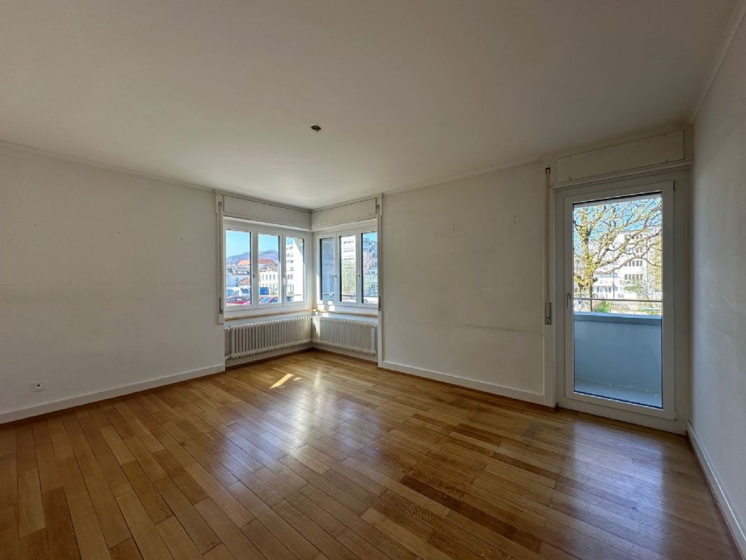 Leerer Wohnraum mit Balkon und Erkerfenstern