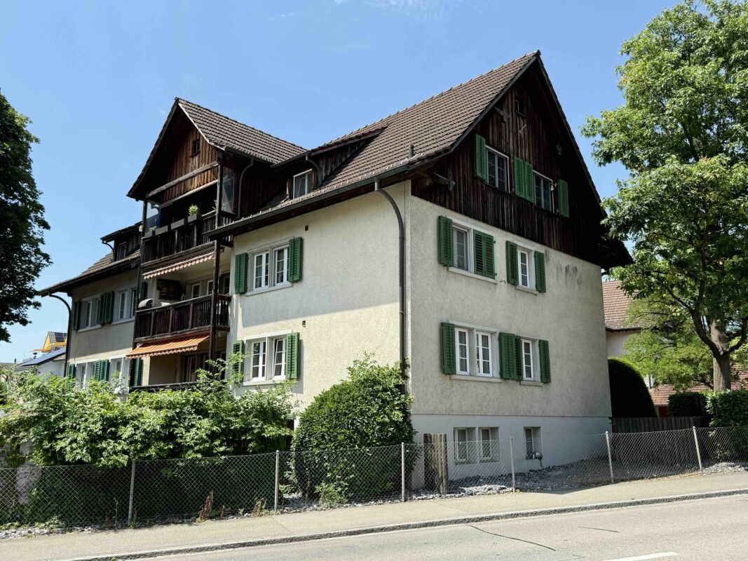 Mehrfamilienhaus mit Holzgiebel und grünen Fensterläden