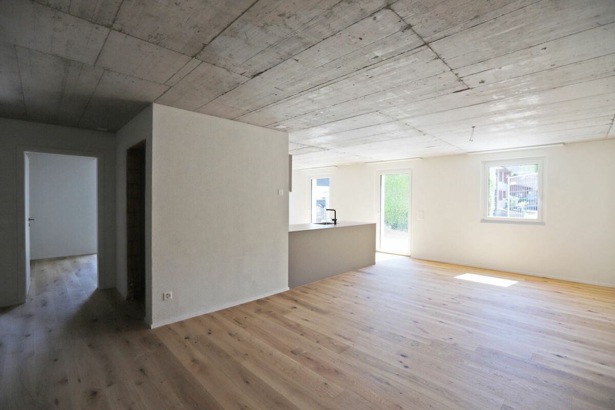 Offener Wohnraum mit Sichtbetondecke und Holzoptikboden