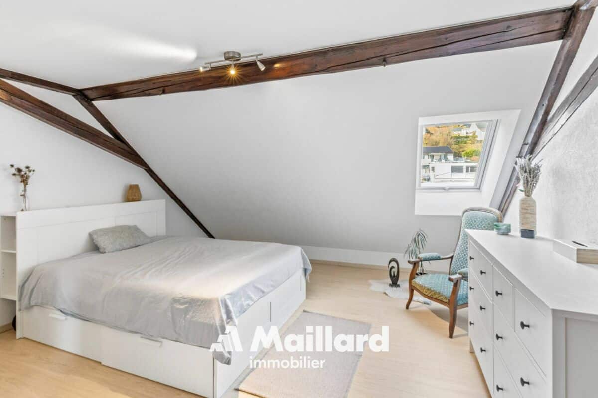 Dachgeschoss-Schlafzimmer mit sichtbaren Holzbalken